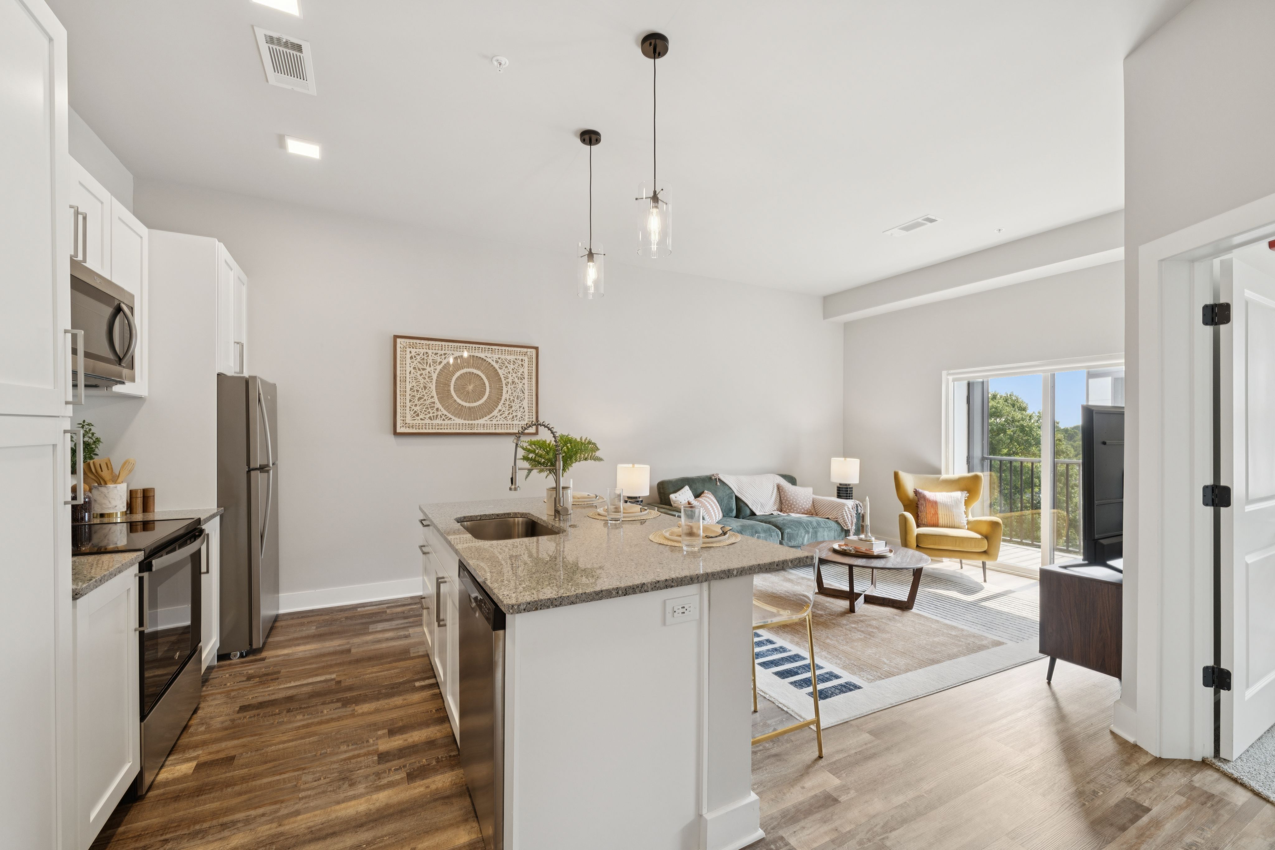 Open concept kitchen and living room featuring modern decor and ample natural light, creating a spacious and inviting atmosphere.