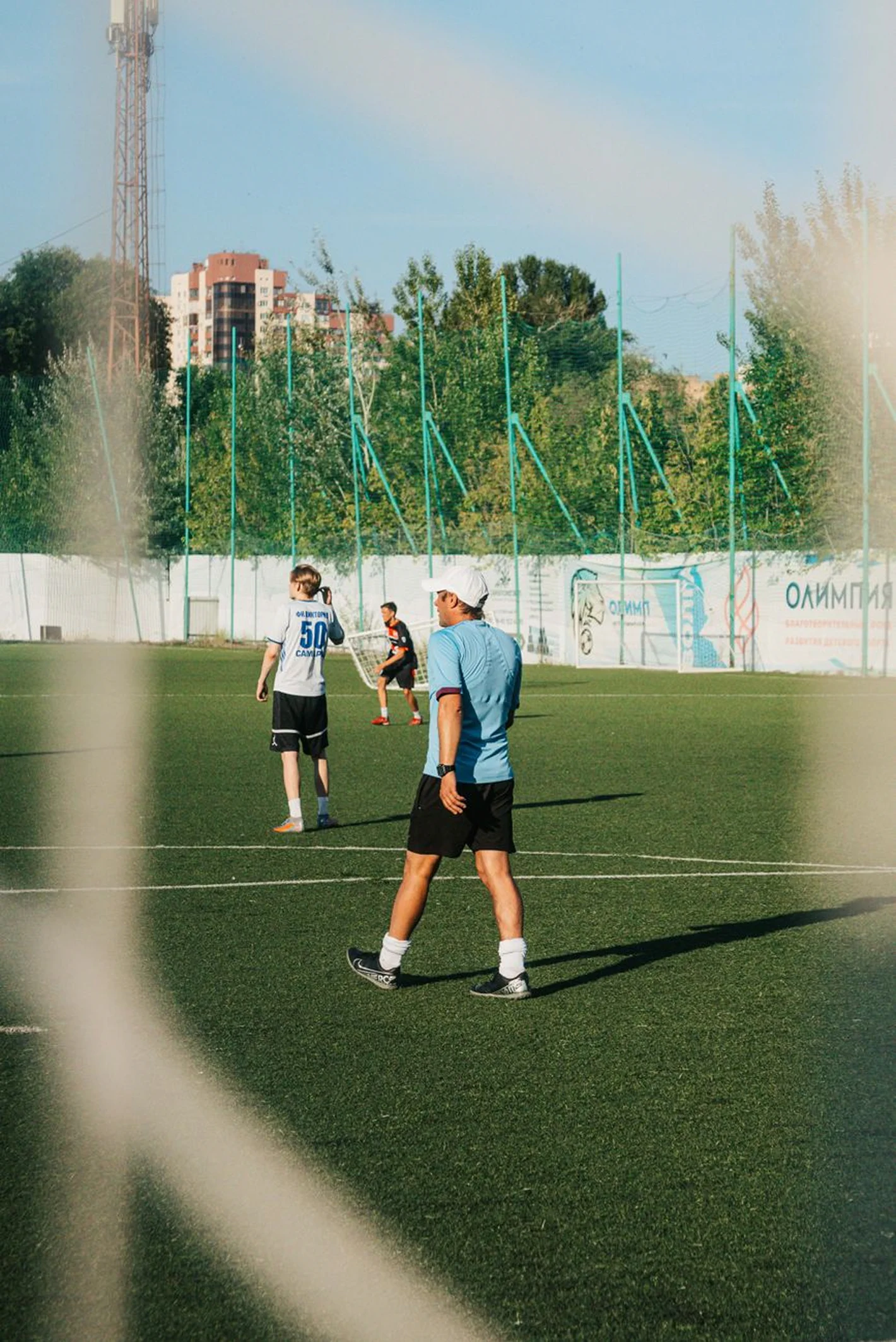 Adult amateur players competing on an enclosed artificial-turf soccer field at night