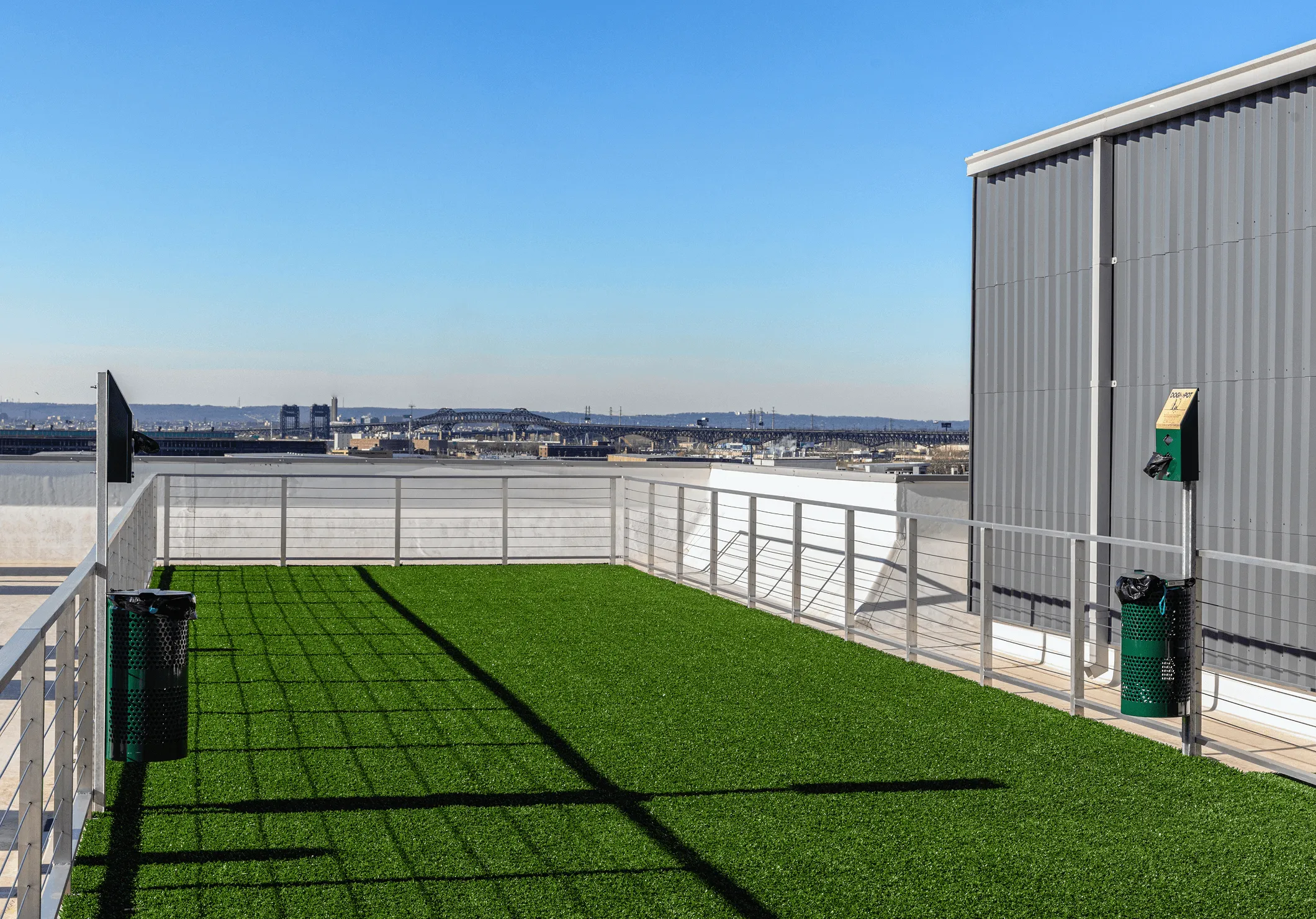 A clear sky above a grassy rooftop with a metal building in the background, extending to a distant landscape.