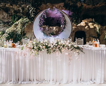 Elegant wedding table setting with floral arrangements, a decorative orb, and lush greenery in the background.