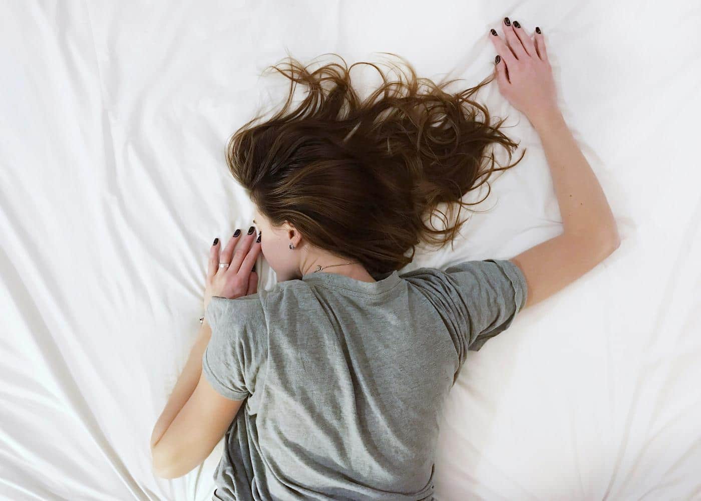 Woman sleeping soundly face down on a white bed