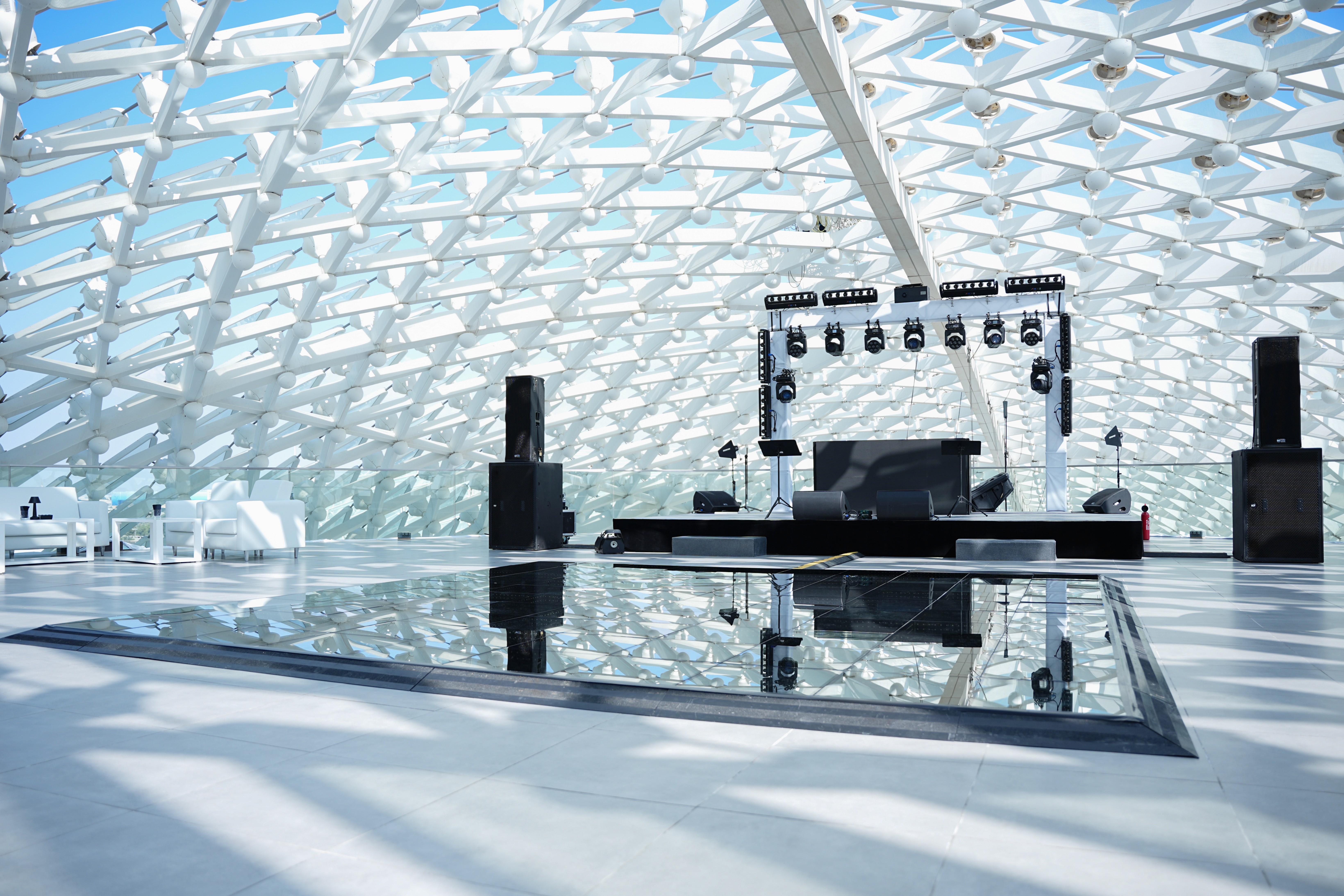 Mature man with glasses and a trimmed beard smiling confidently, standing in warm natural light against a modern backdrop.