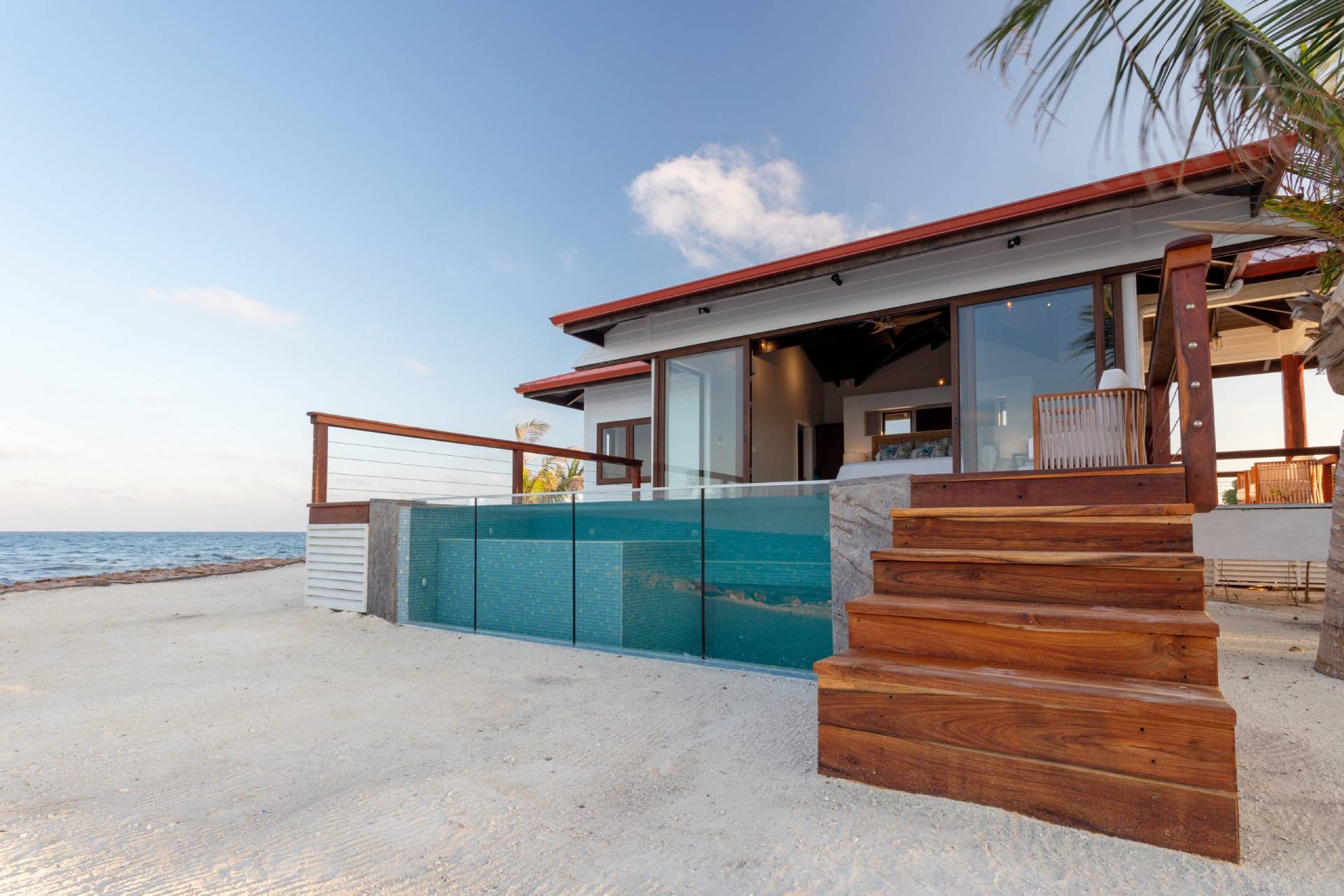 Front side of one of the luxurious acommodation options at Ray Caye with white sand beach and a translucent private pool