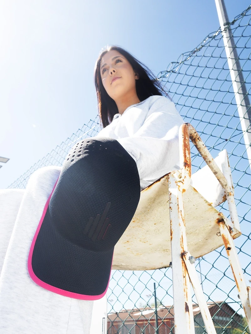 Casquette noire The Prompt Factory mise en avant lors d’un shooting sur un court de tennis