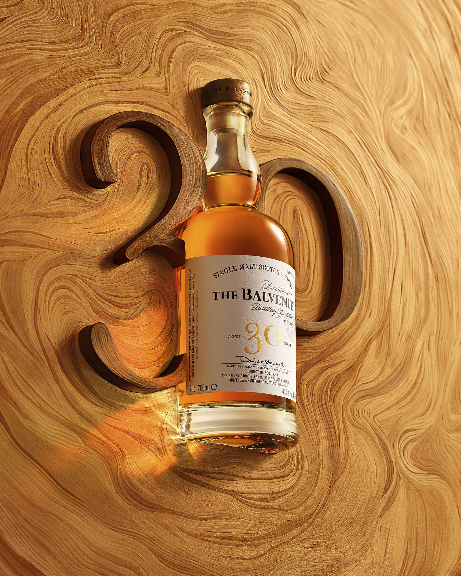 A bottle of whiskey positioned on a wooden surface with the number "30" carved into it