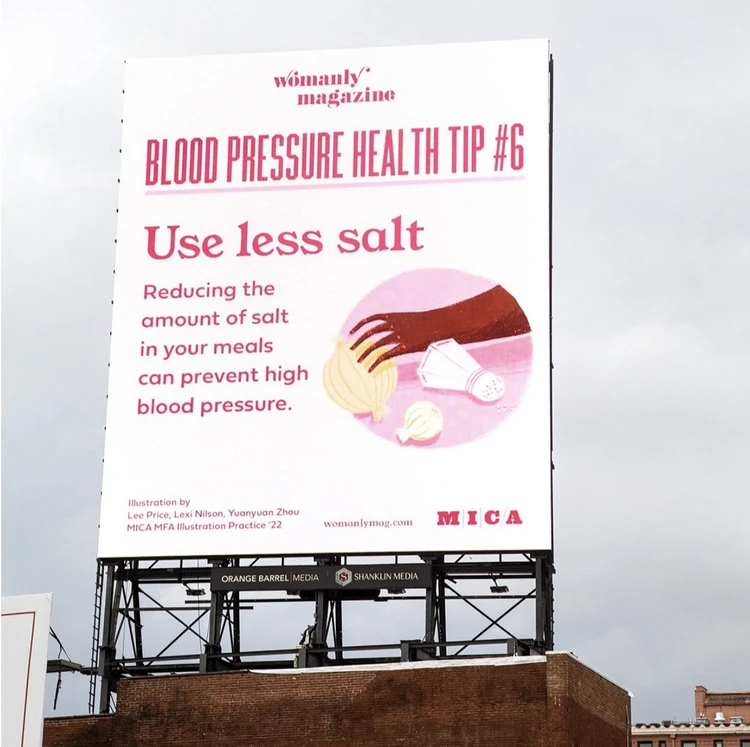 A large billboard for "Womanly Magazine" displays "Blood Pressure Health Tip #6: Use less salt," with an illustration of salt, onions, and garlic, emphasizing the importance of reducing salt to prevent high blood pressure.