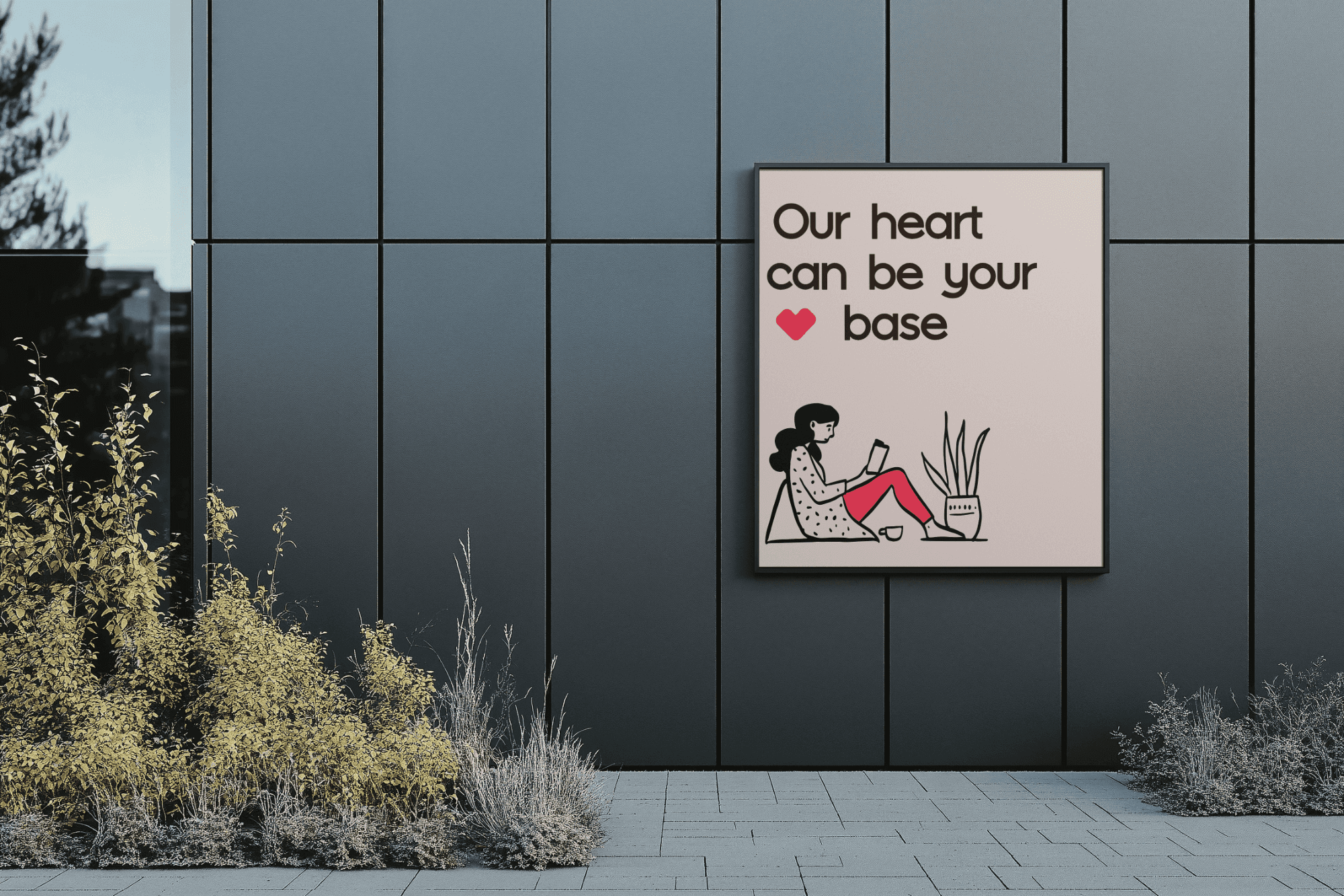 A modern, minimalist wall display featuring a framed illustration of a person reading in a relaxed posture near a potted plant, complemented by the phrase "Our heart can be your base," is set against a sleek, dark paneled background with subtle greenery in the foreground.