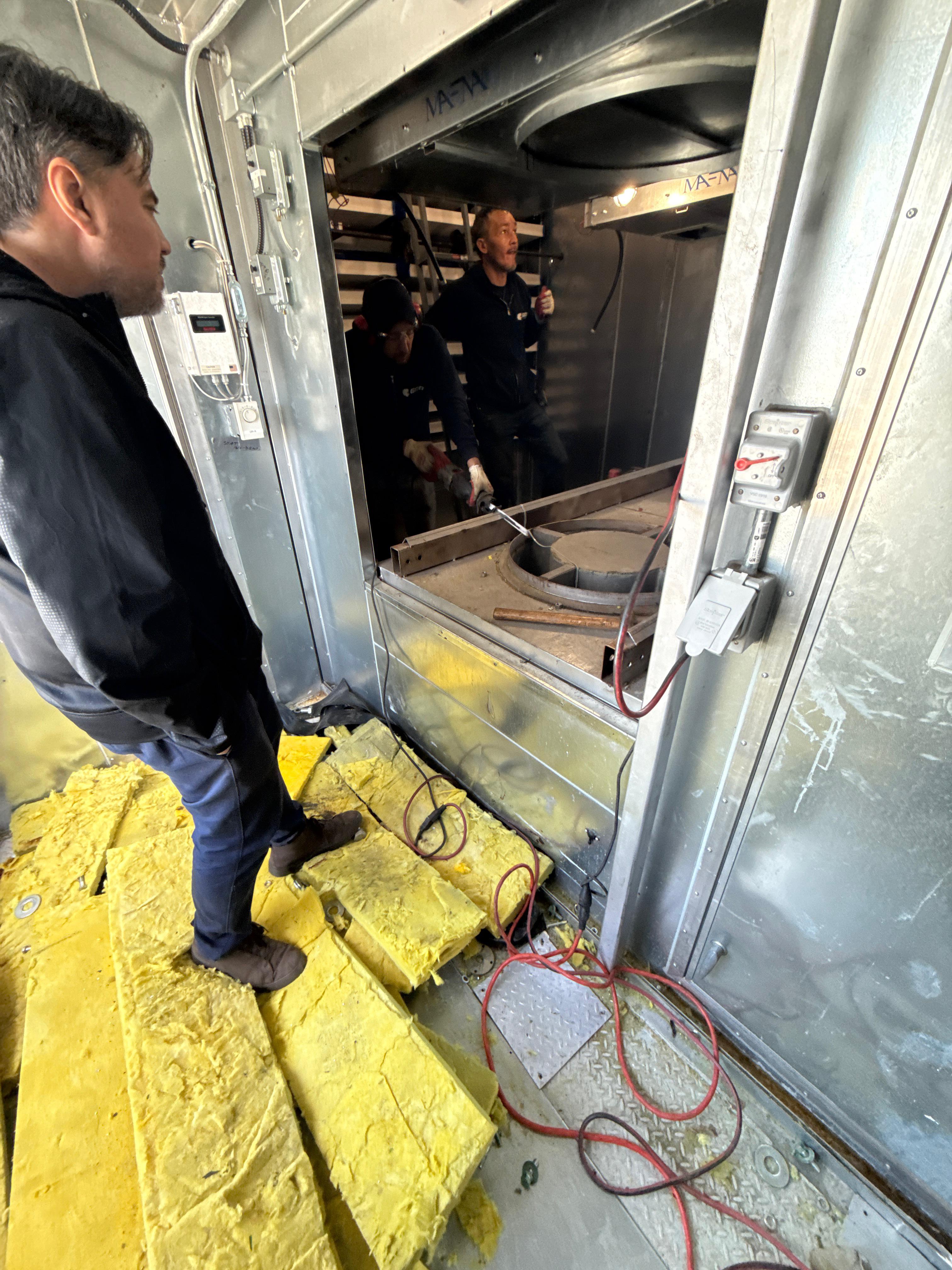 Legacy fan equipment inside a hospital air handling unit prior to retrofit, with access panels open during AHU modernization work in New York City.