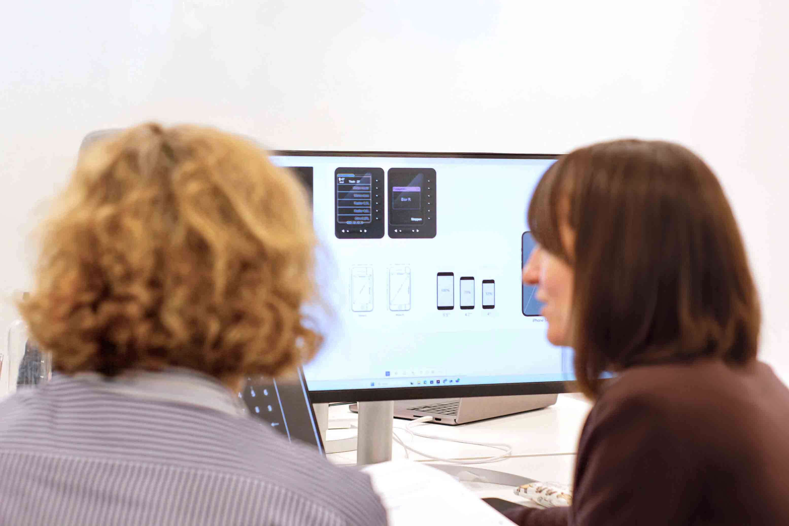 Carlotta Katahara and Sabine Ivey-Frank working together on the screens of an app.