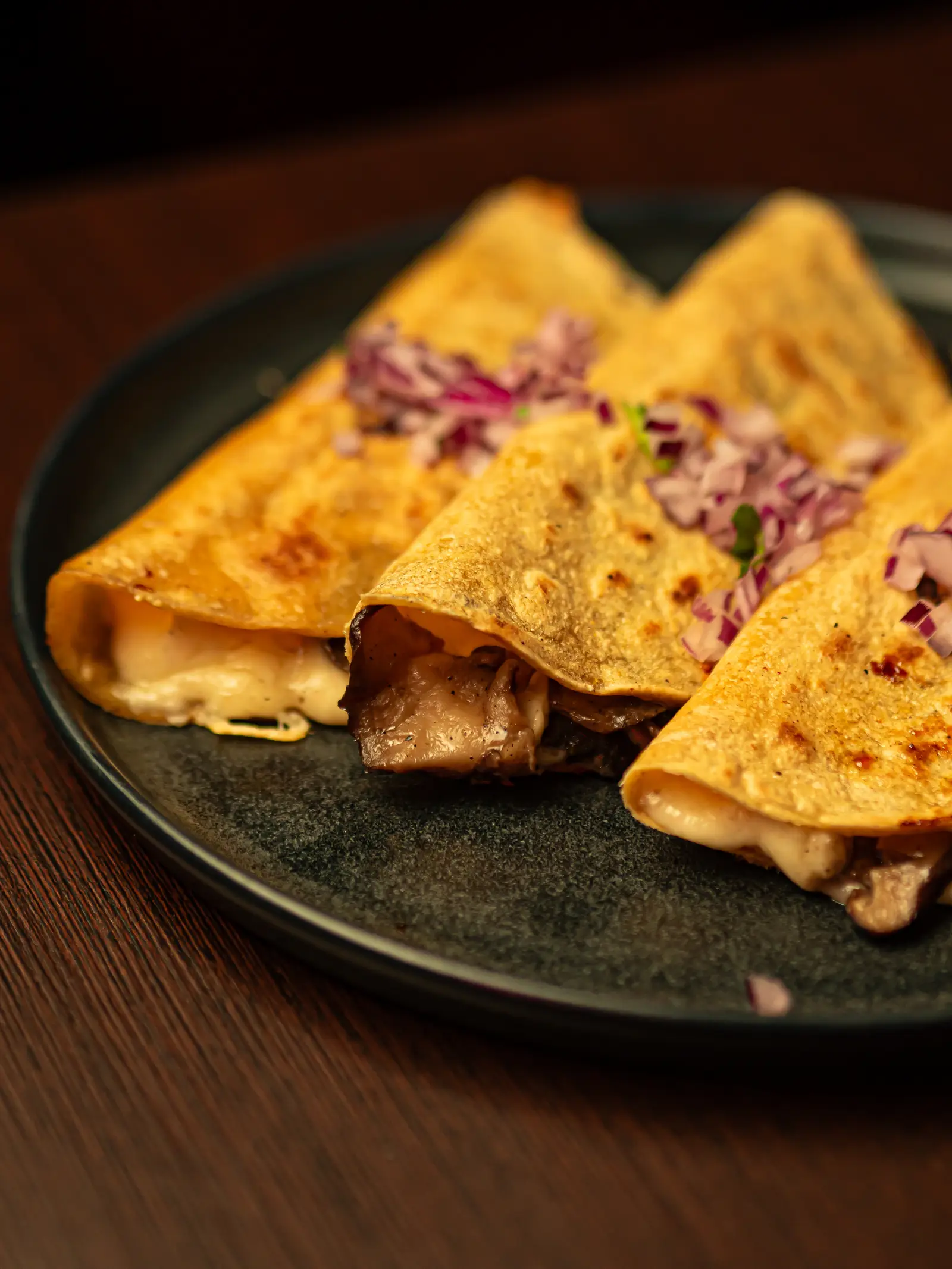 Quesadillas de setas en recado negro con queso de bola y cebolla morada