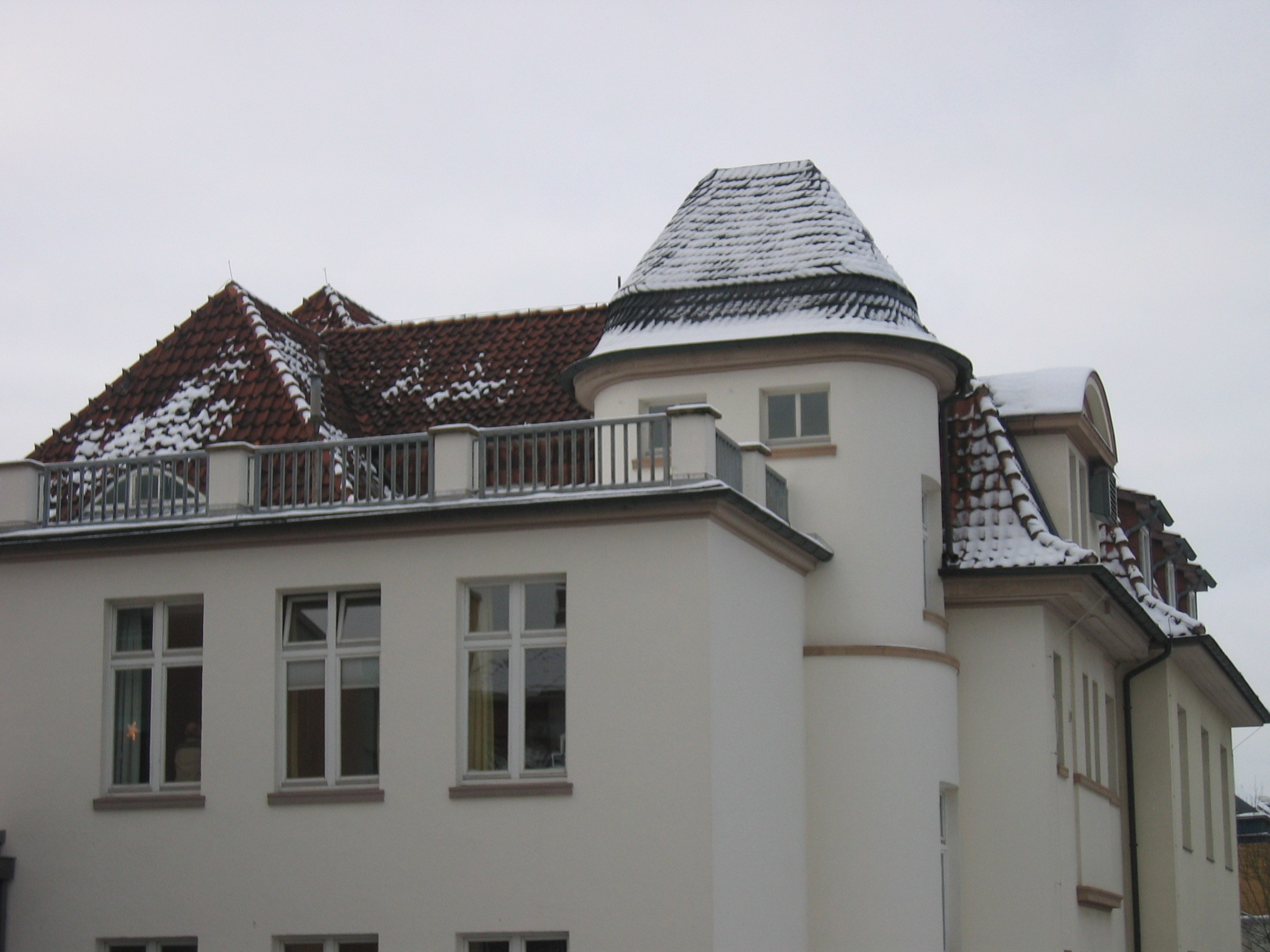 Weiße Fassade und rotes beschneites Dach der Frauenklinik