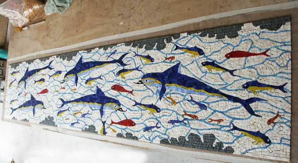 Vibrant mosaic fish artwork with blue, red, and yellow tiles.
