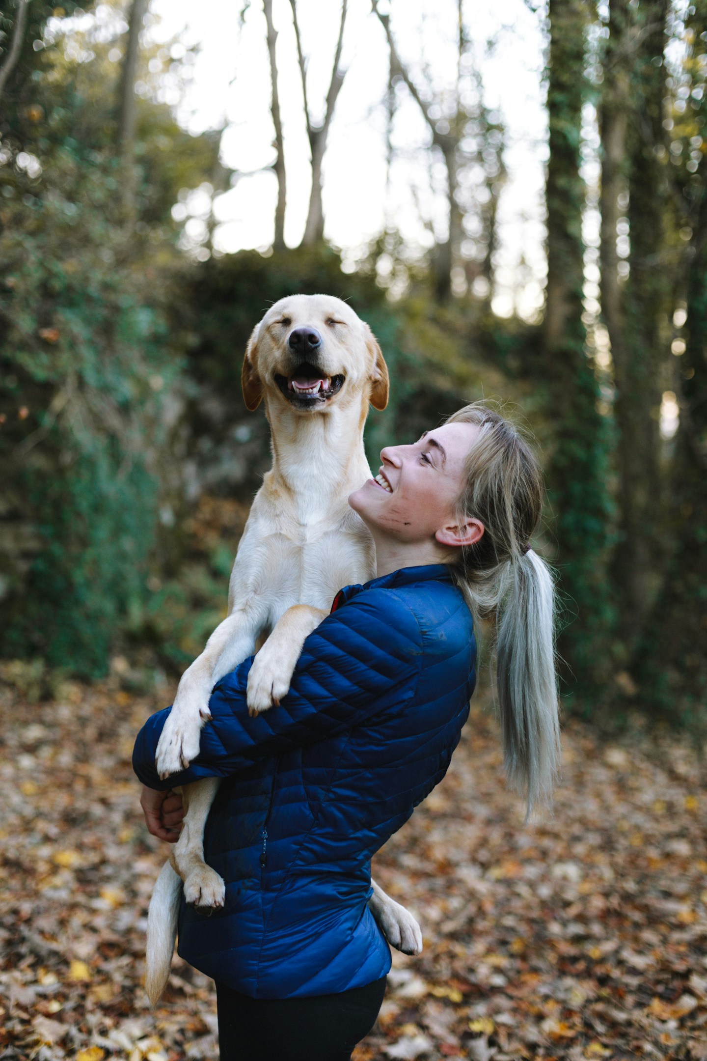Priya Shah, senior groomer, laughing while holding a happy labrador