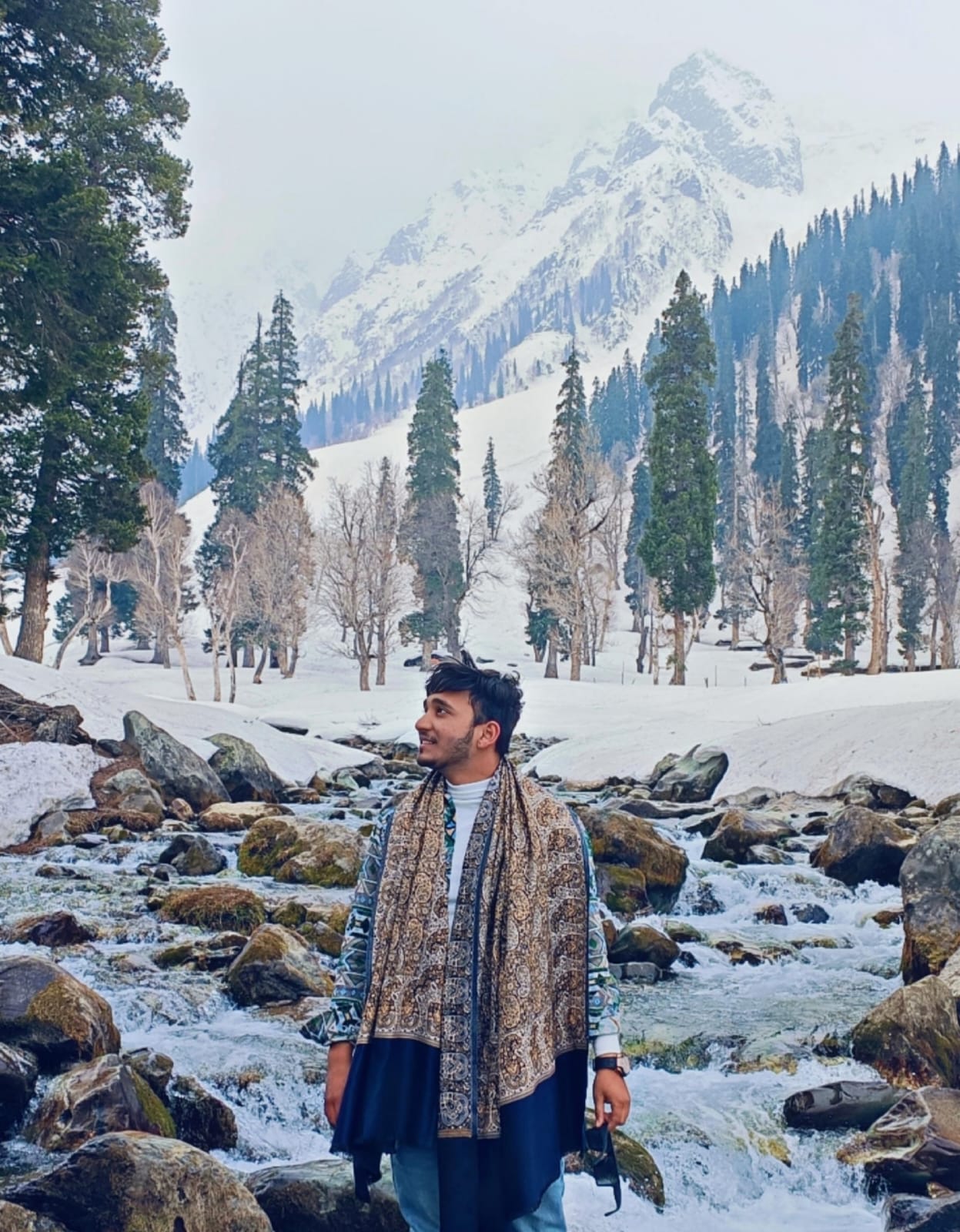 Adnan standing beside a stream in the mountains