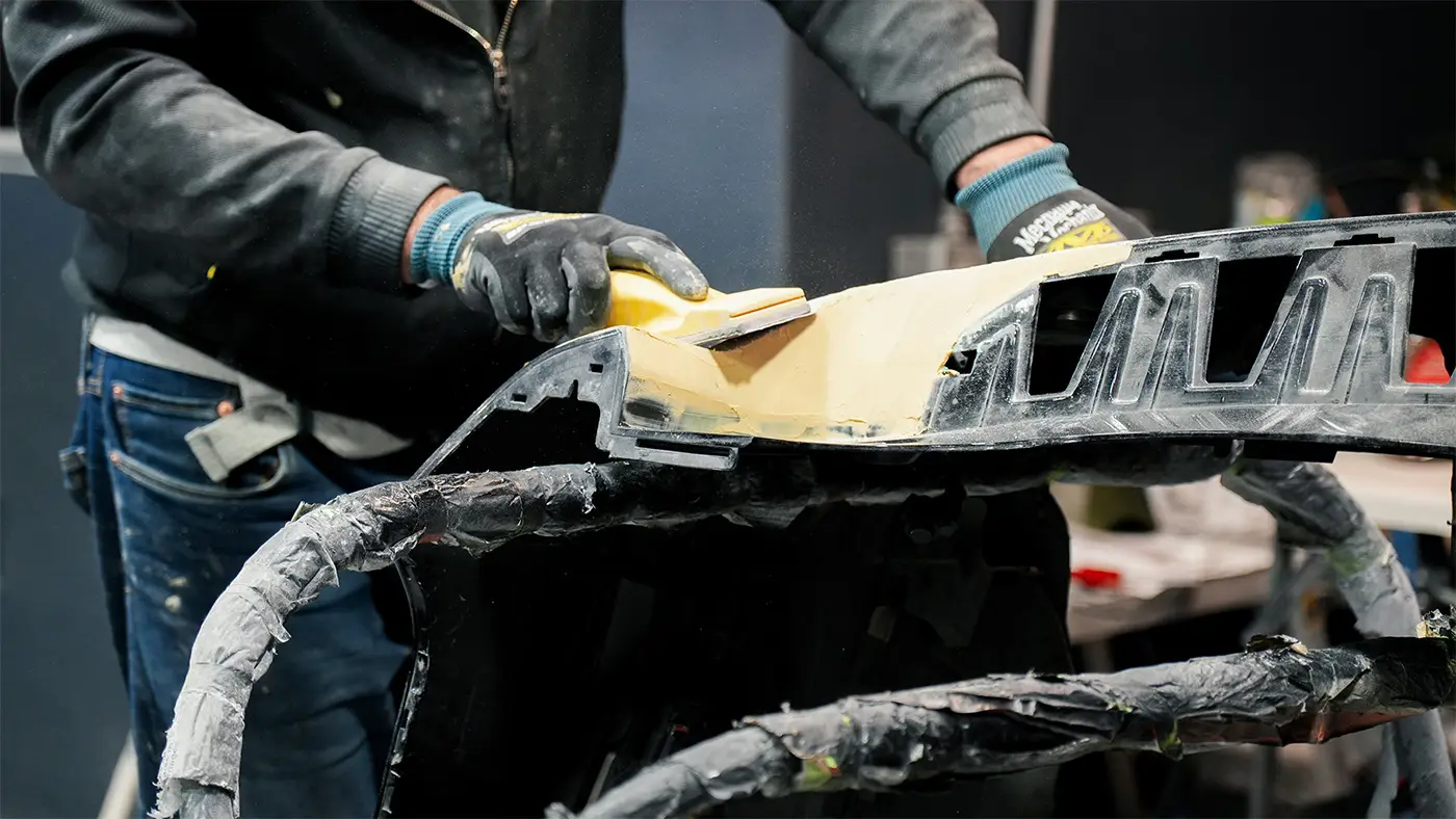 Auto Body Unlimited technician repairing and reshaping a vehicle bumper.