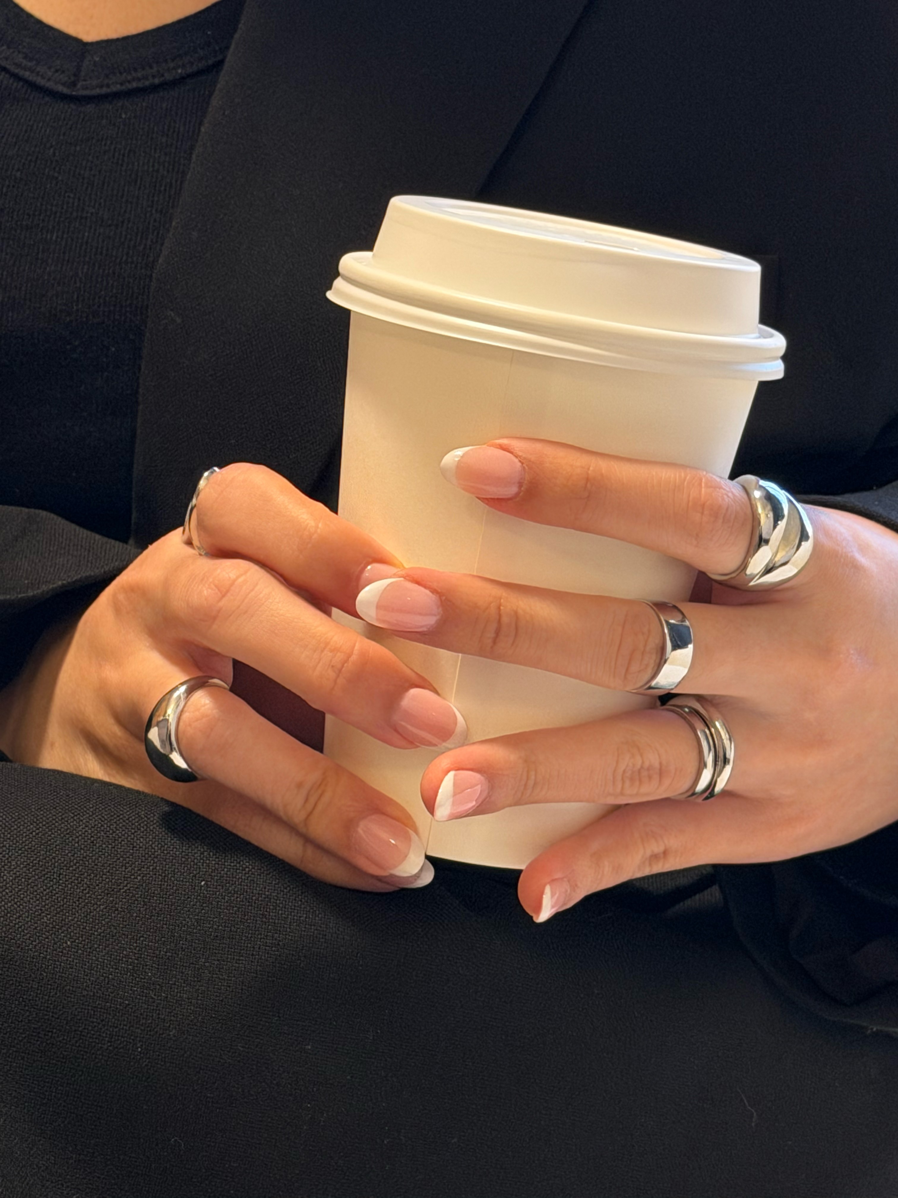 A luxurious bathtub filled with water and floating rose petals, surrounded by candles and greenery. The soft lighting creates a tranquil and romantic spa-like atmosphere.