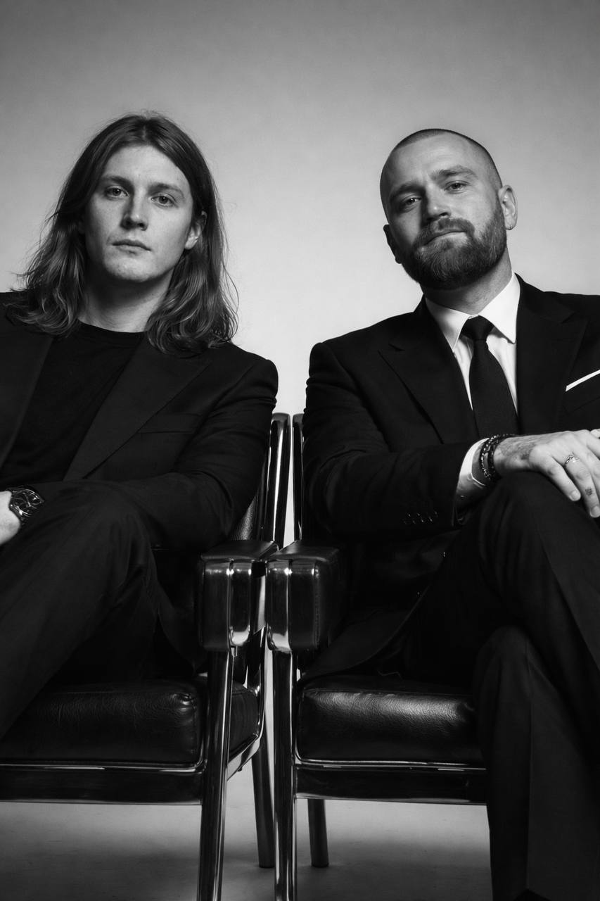 Woman in red outfit poses by a red telephone booth.