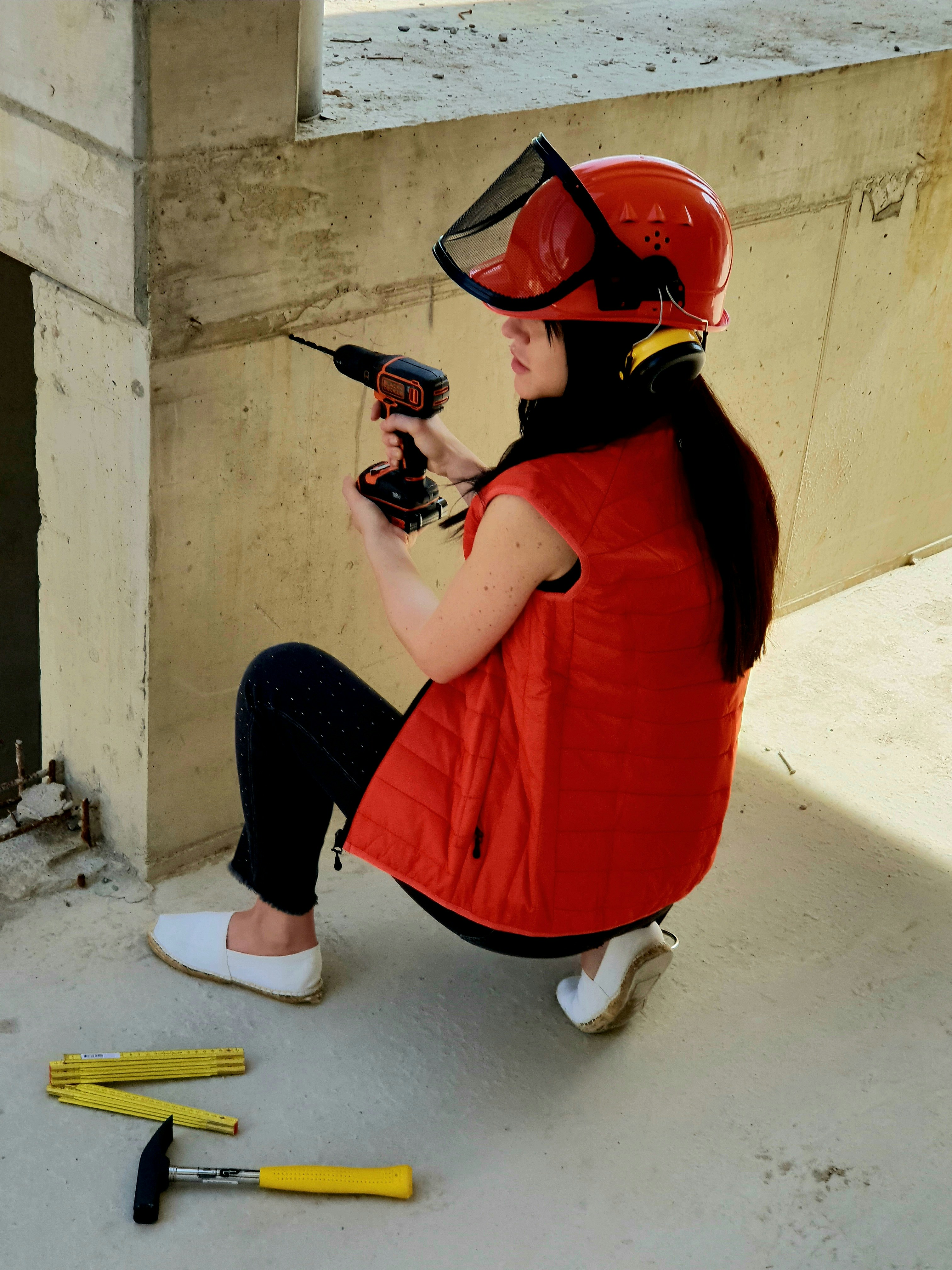 a woman sitting on the ground holding a drill