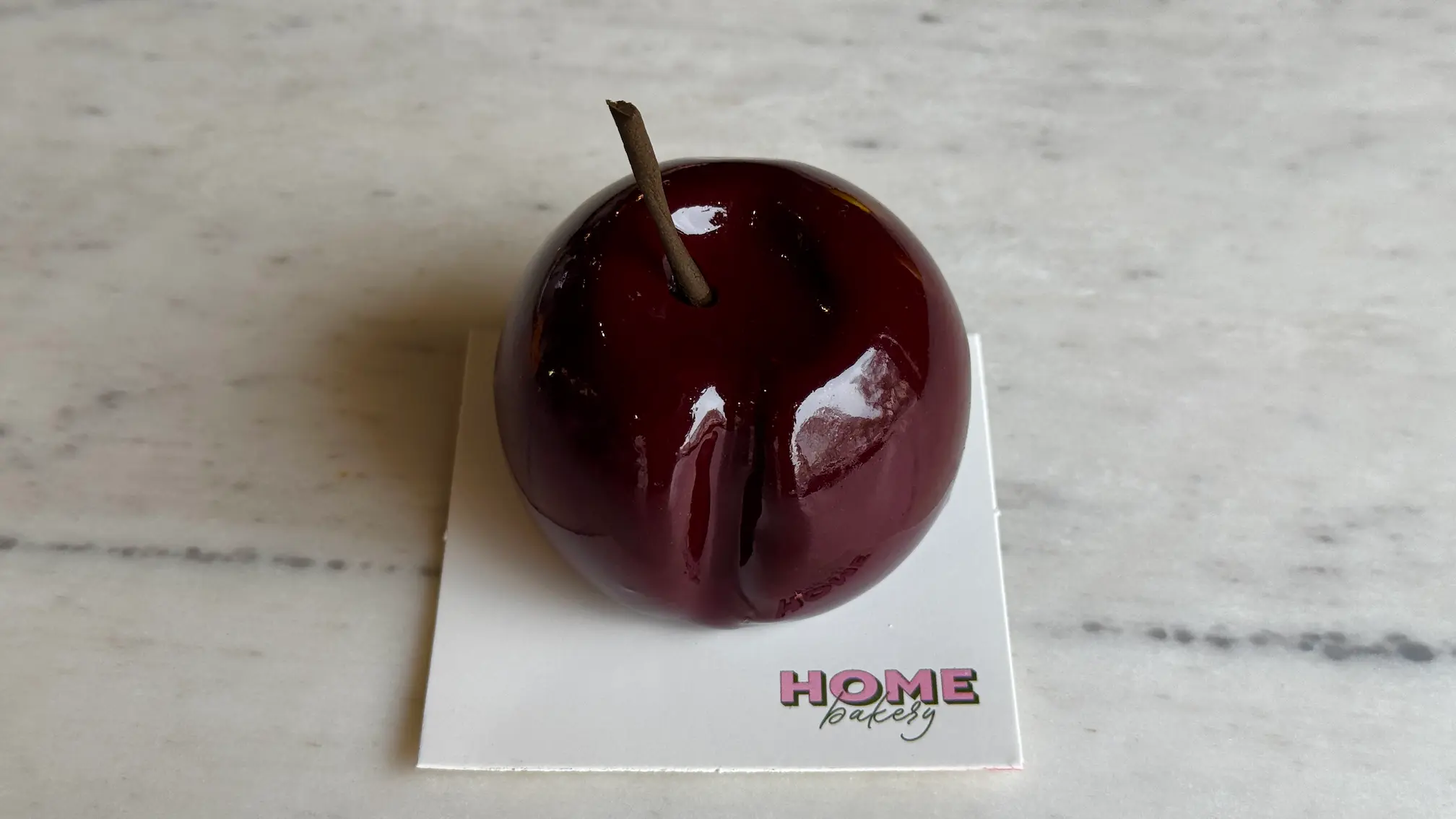 Cherry-shaped mousse cake with glossy burgundy glaze and chocolate stem