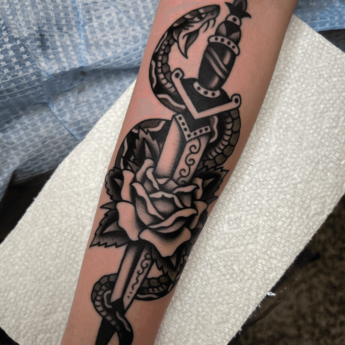 black and gray tattoo of a dagger, rose, and snake