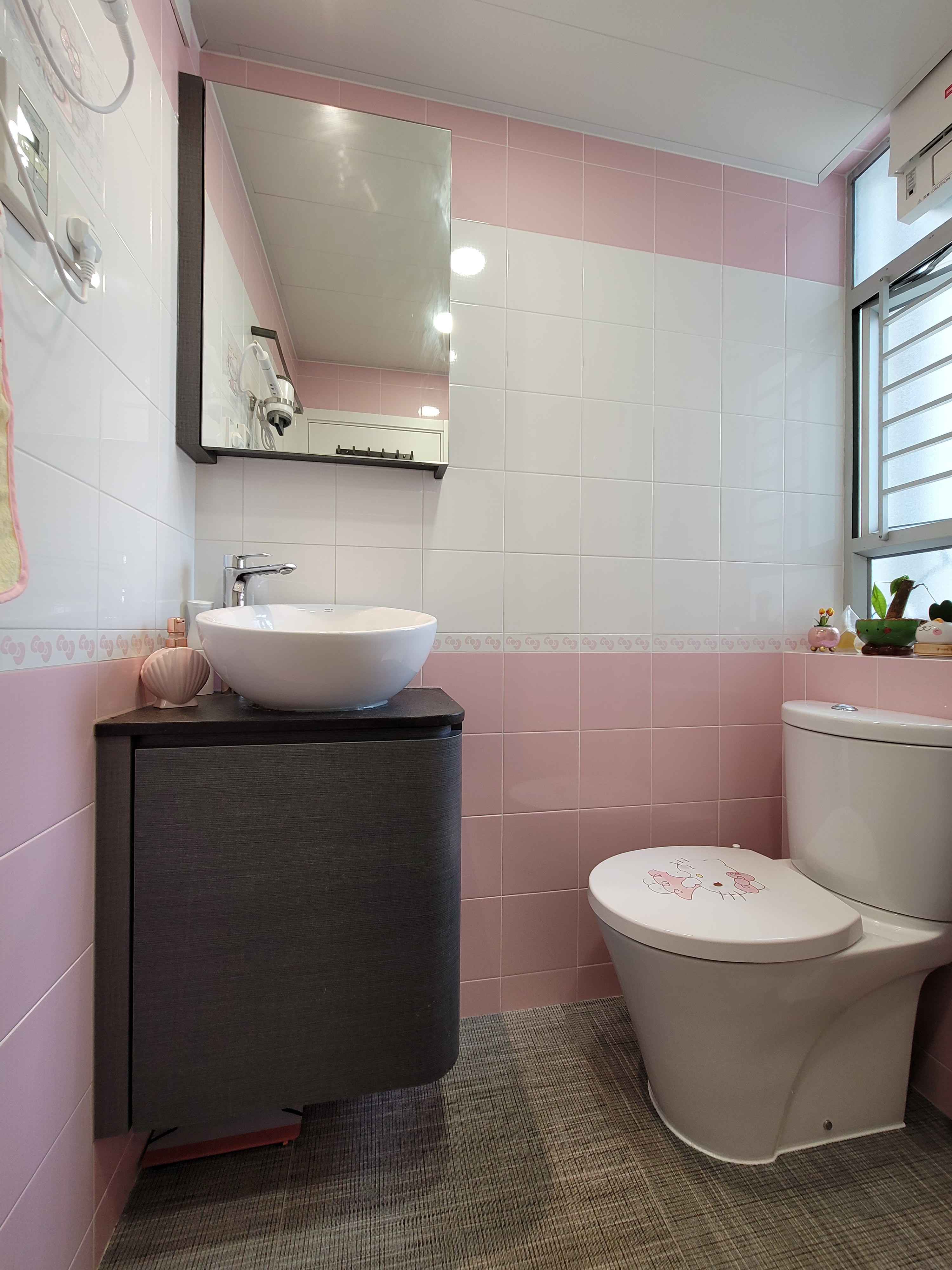 Pink bubble tea umbrella holder placed against a white door and pink tiled walls in a Hoi Tat Estate bathroom.