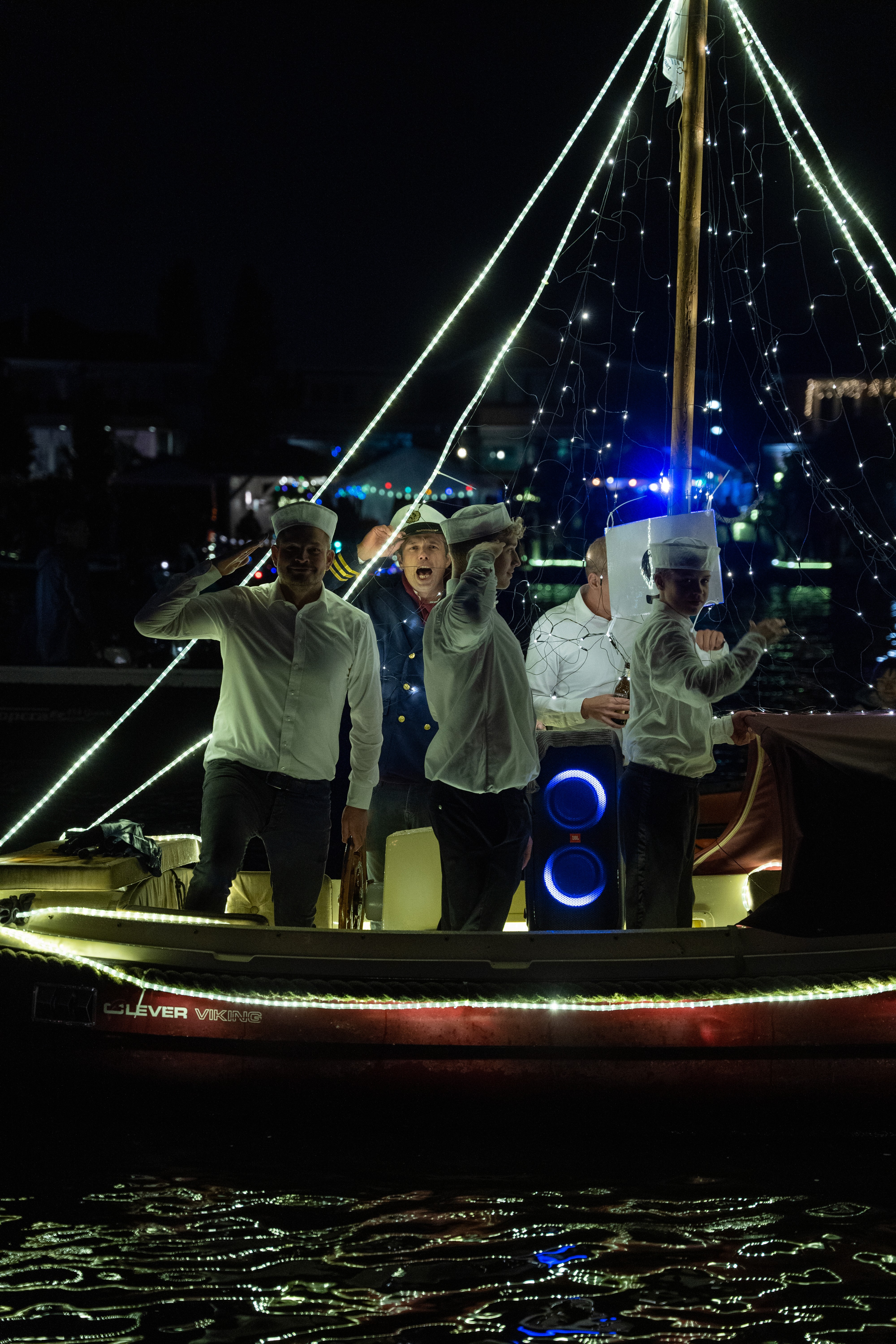 Close-up of a male runner in a red jersey and black shorts, wearing a smartwatch, mid-stride during a race.