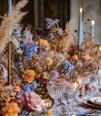 A beautifully arranged table centerpiece featuring dried flowers and elegant candles in a warm, inviting setting.