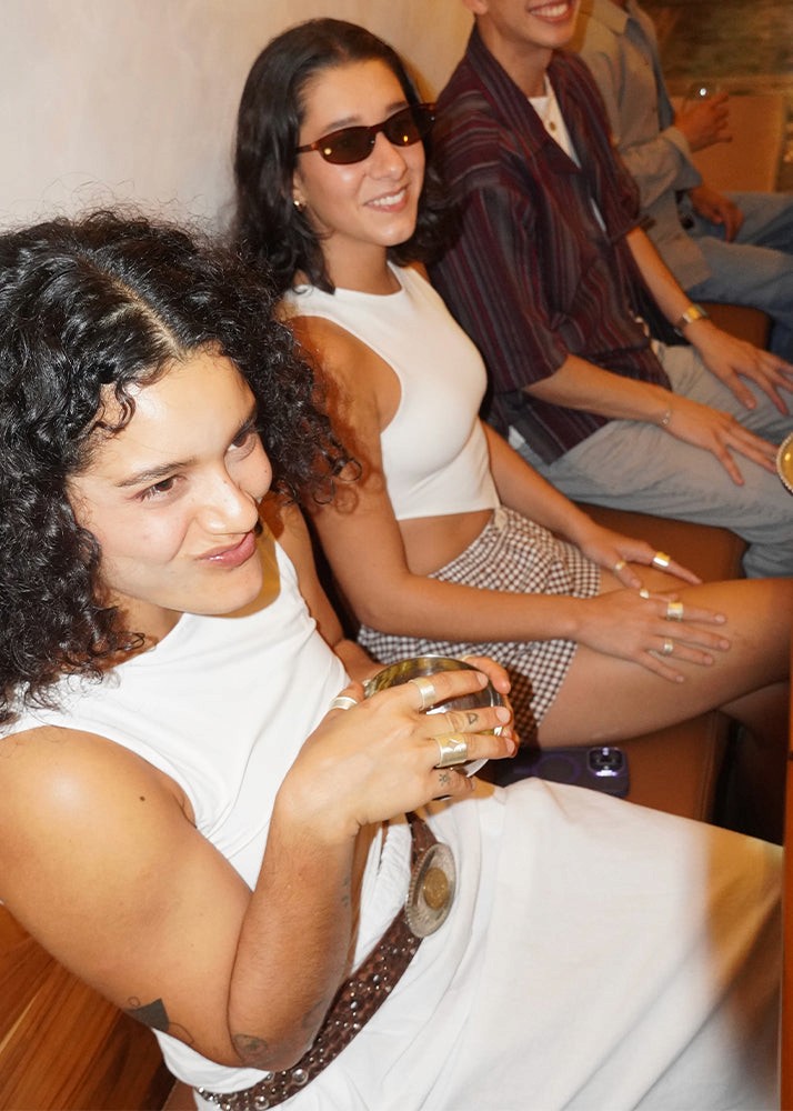 Two women sitting together, one holding a drink, with a casual setting.