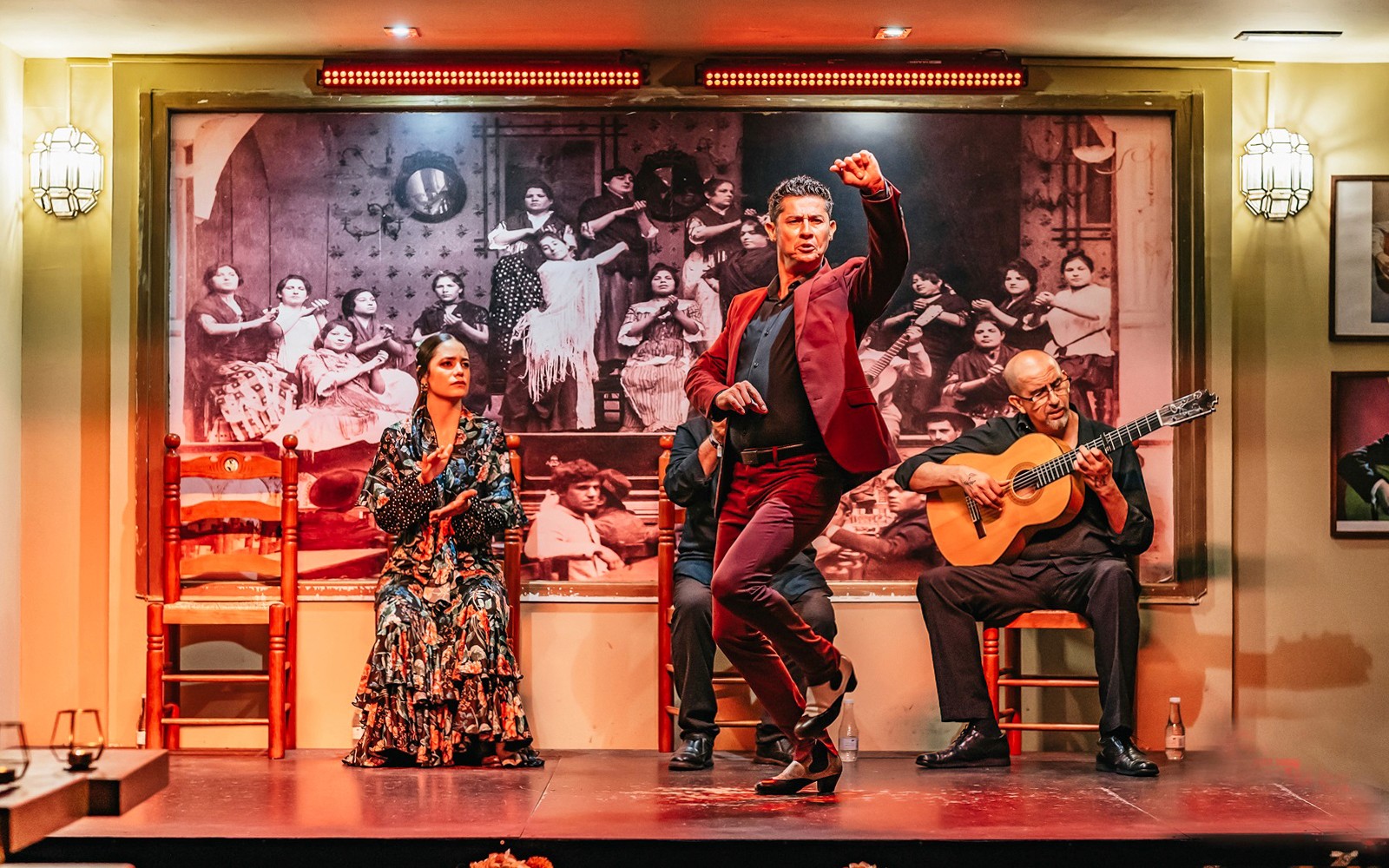 Flamenco dancer performing with guitarist and singer in a vibrant show setting.