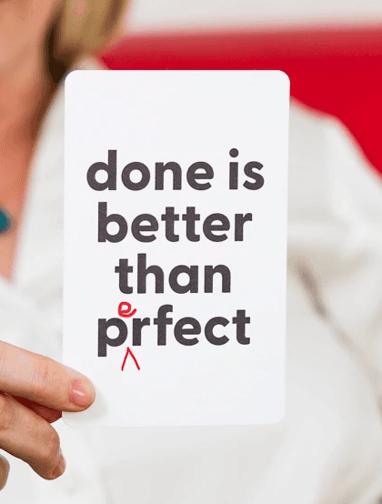 Person holding a card with the motivational quote done is better than perfect