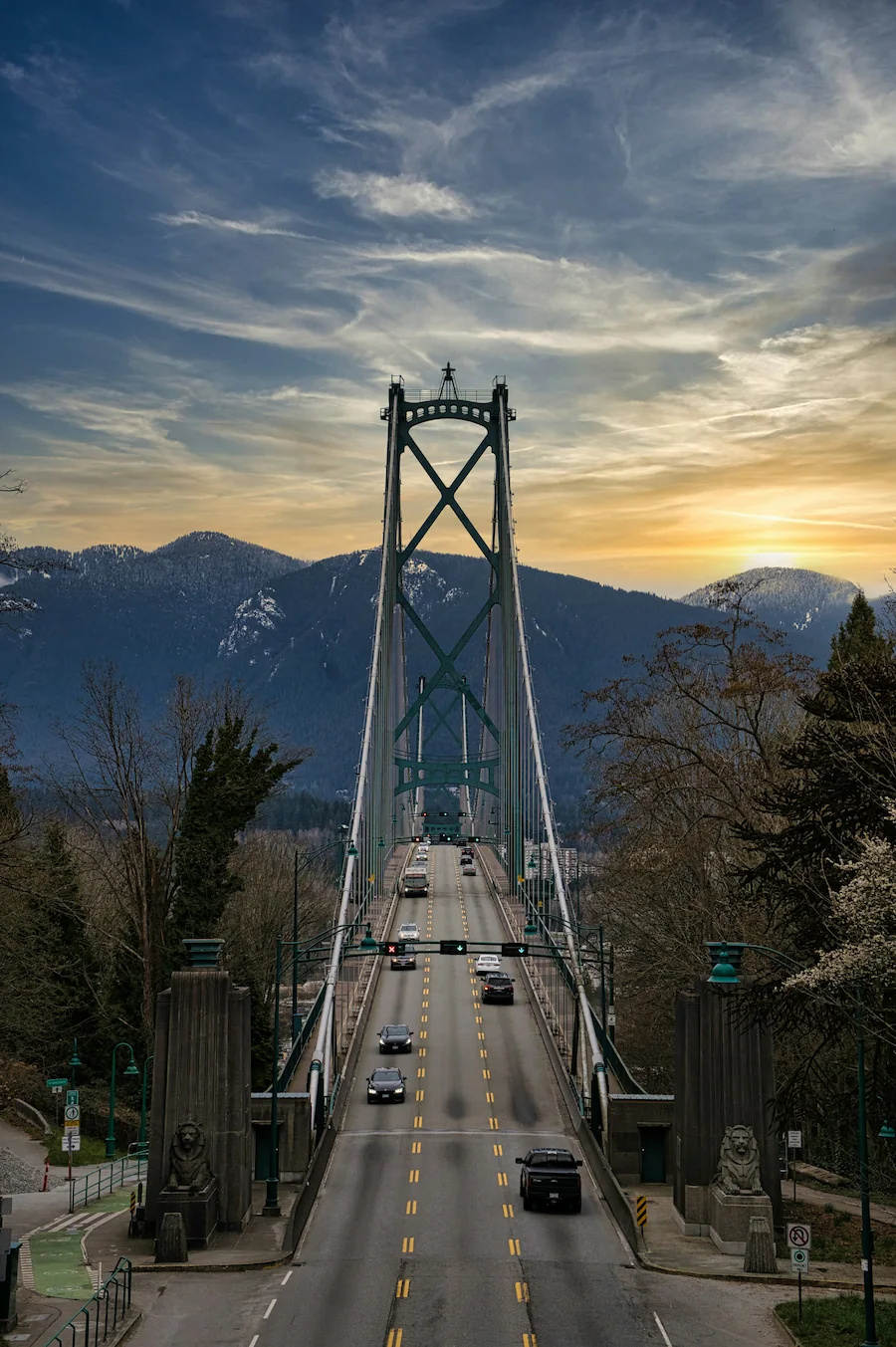 Head-on view of Vancouver’s Lions Gate Bridge with cars crossing toward forested North Shore mountains.