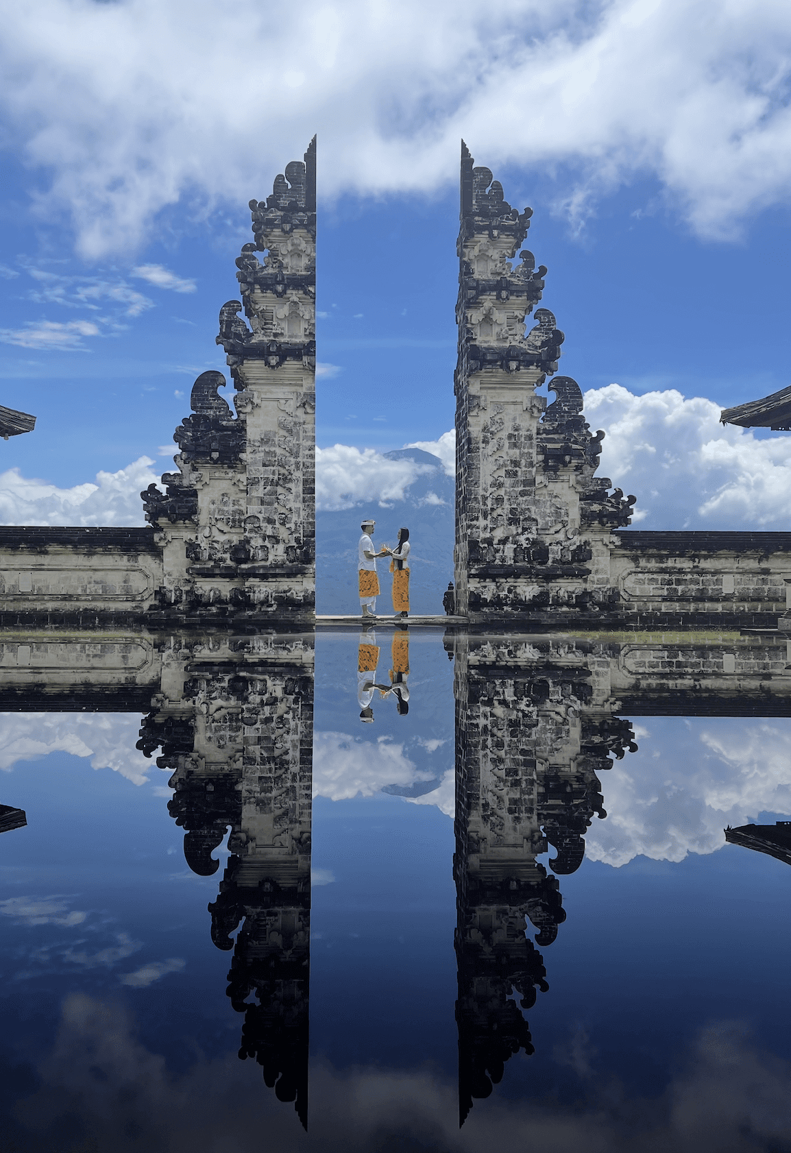Couple making heart shape with hands in countryside wildflower field