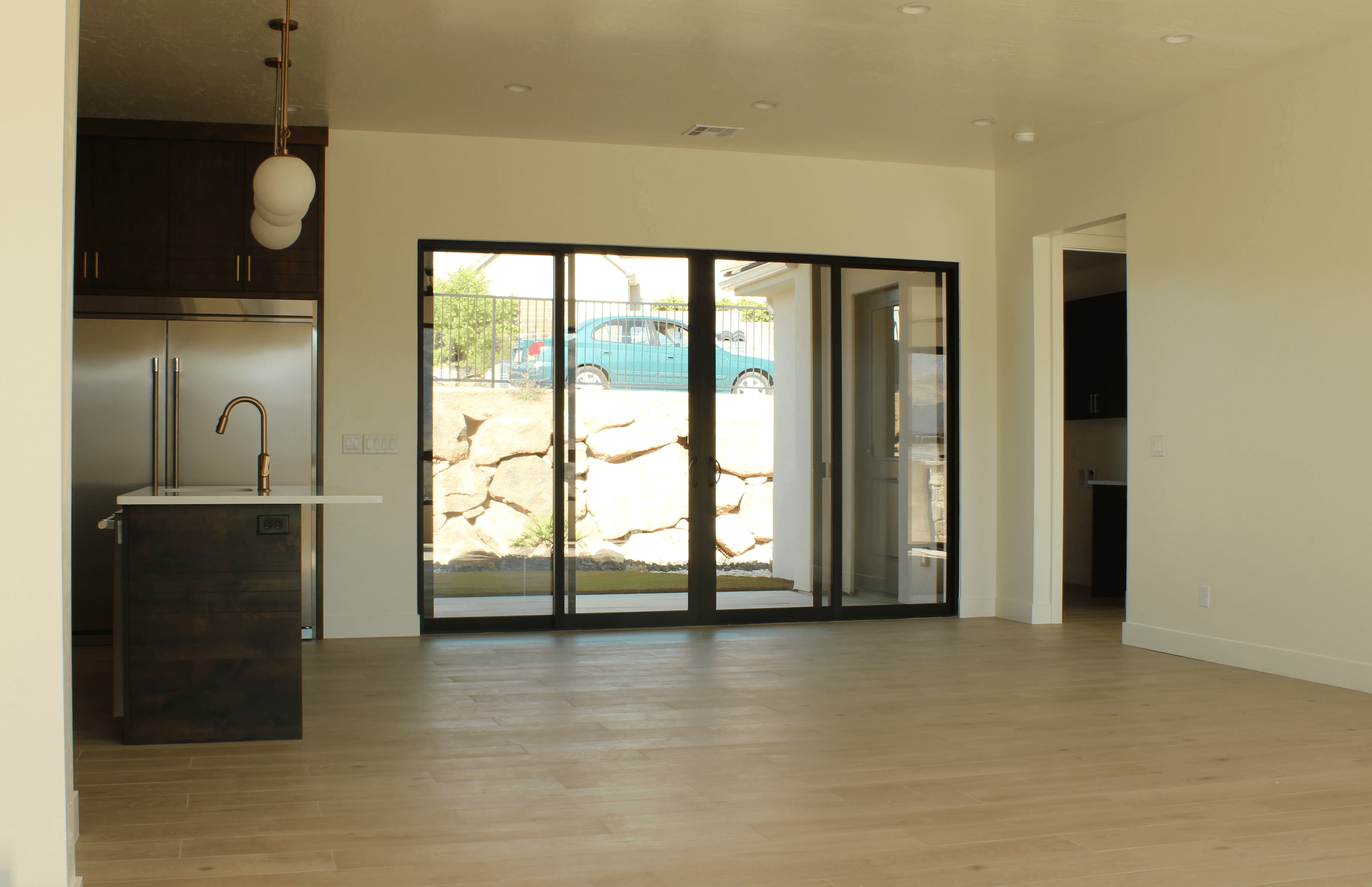 Great room with hard surface flooring, kitchen island, and sliding glass door opening to backyard in a Southern Utah home