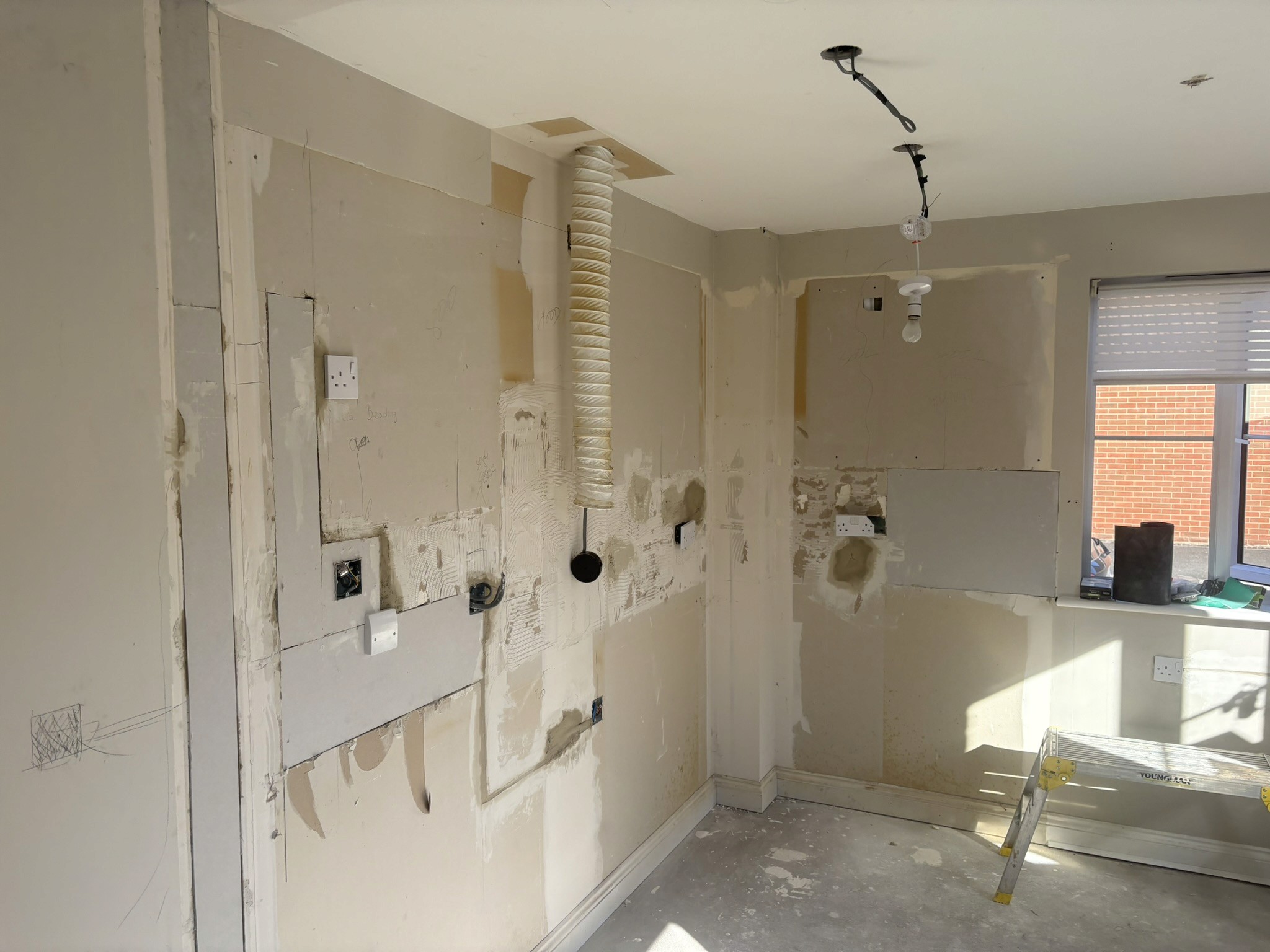 Kitchen renovation in progress, with units removed and exposed wall surfaces and service points.