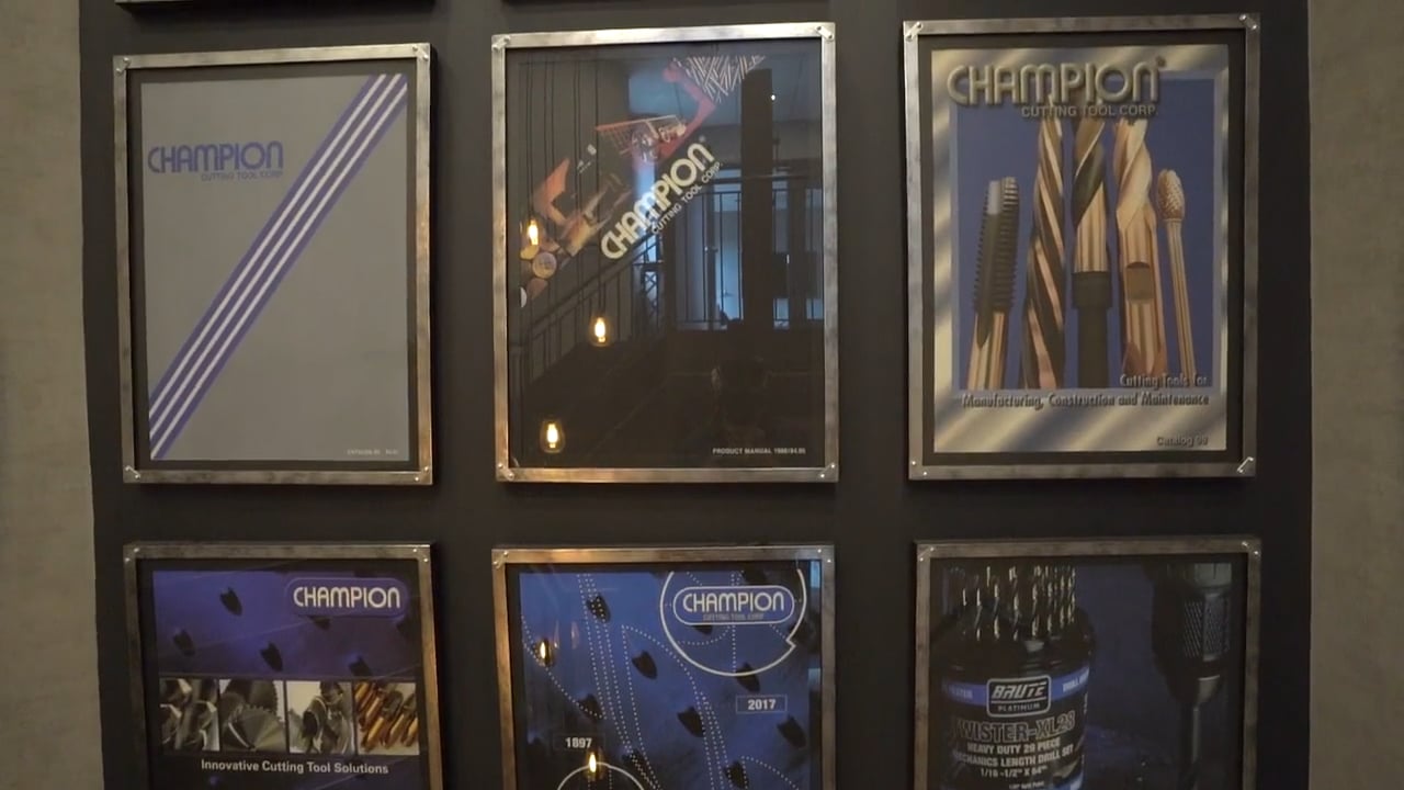 The image shows a wall display featuring six framed posters showcasing "Champion" branded cutting tools and innovative tool solutions, each with unique designs and photography highlighting the product range.