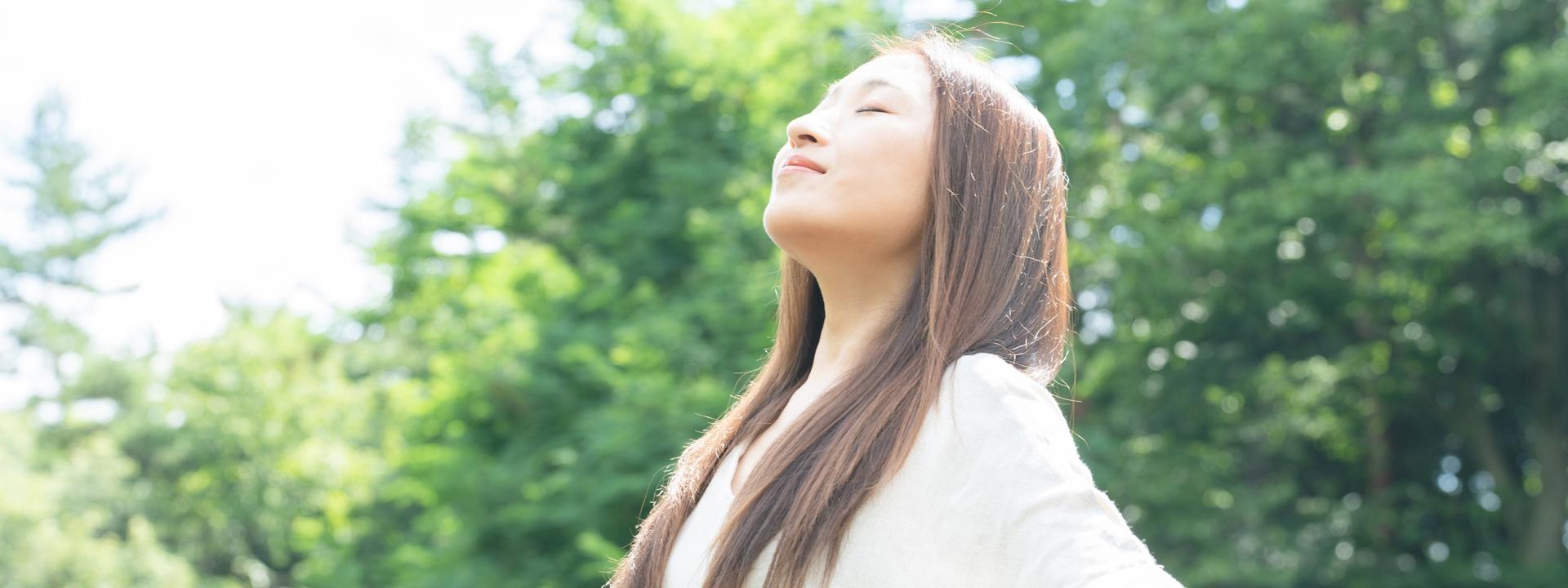 自然の中で深呼吸をする女性