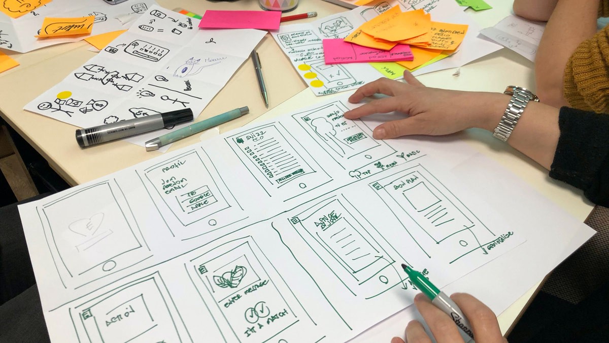 UX designer sketching app wireframes during a design thinking workshop.
