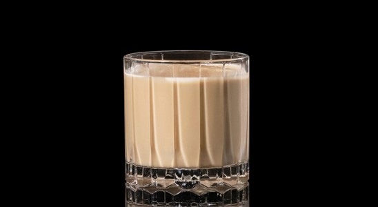 A closeup of a White Russian drink against a dark background.