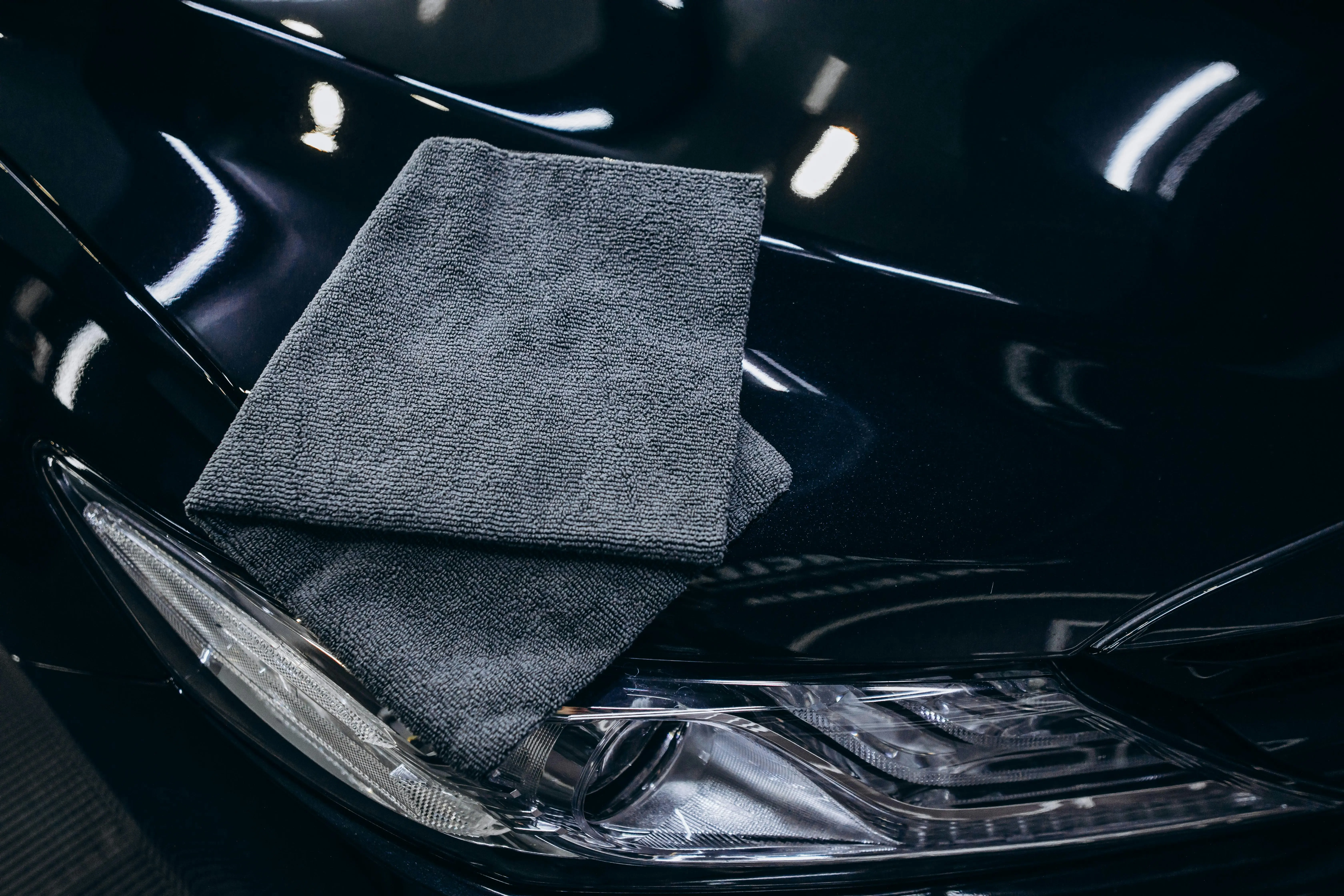 Gray microfiber cloth on a black car hood.