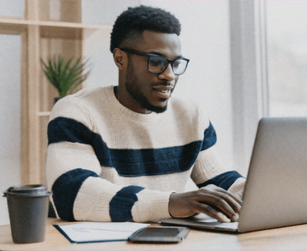 Man sitting in a dimly lit room, wearing a beige shirt and looking contemplative.