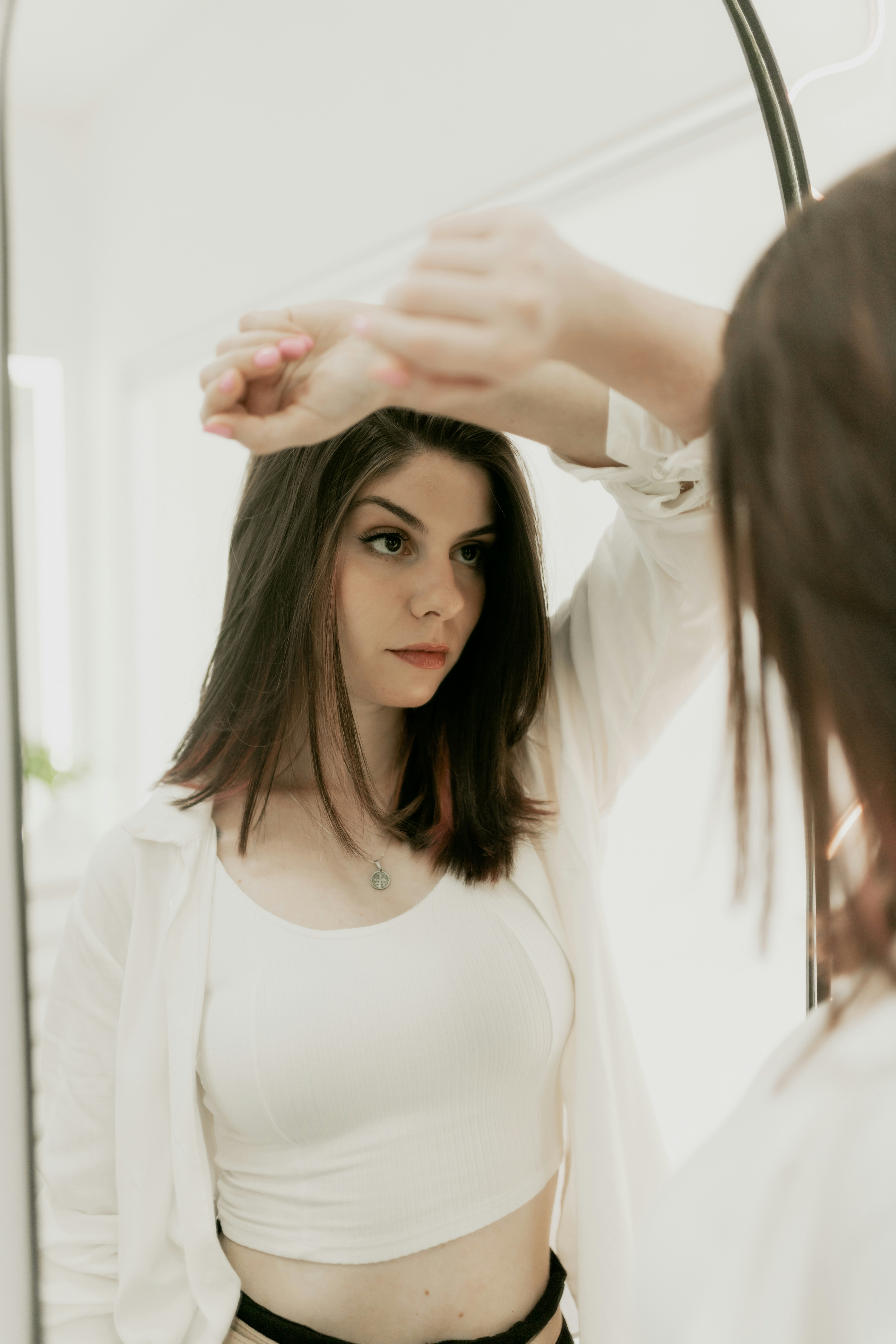 A woman standing in front of a mirror brushing her hair