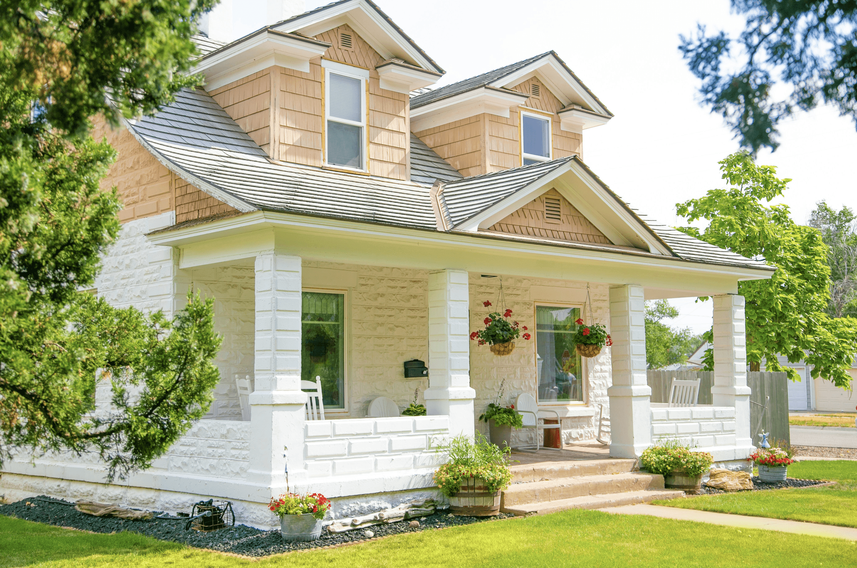 Charming two-story home with porch, white brick, and flower boxes. Real estate.