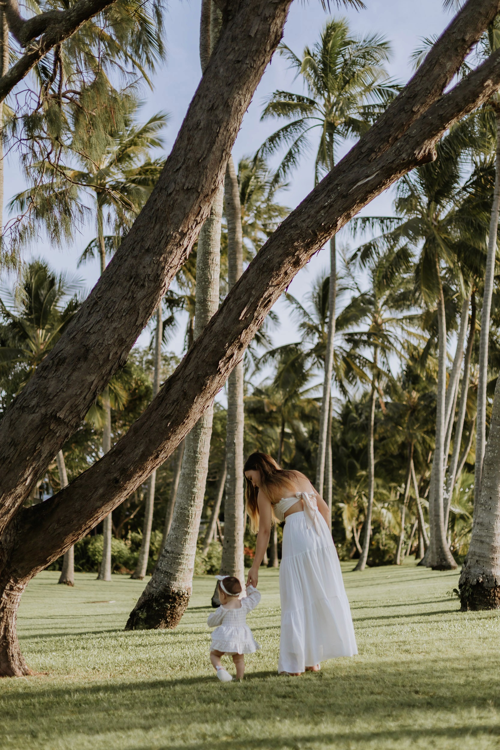 Daughter walking beside her mother under palm trees during a natural family photo session
