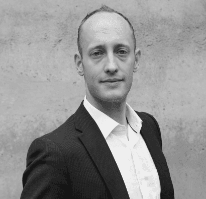 black and white photo of the upper part of a man in a suit and white shirt without tie and with his arms crossed. this is the CEO of BeyondTrucks, Hans Galland