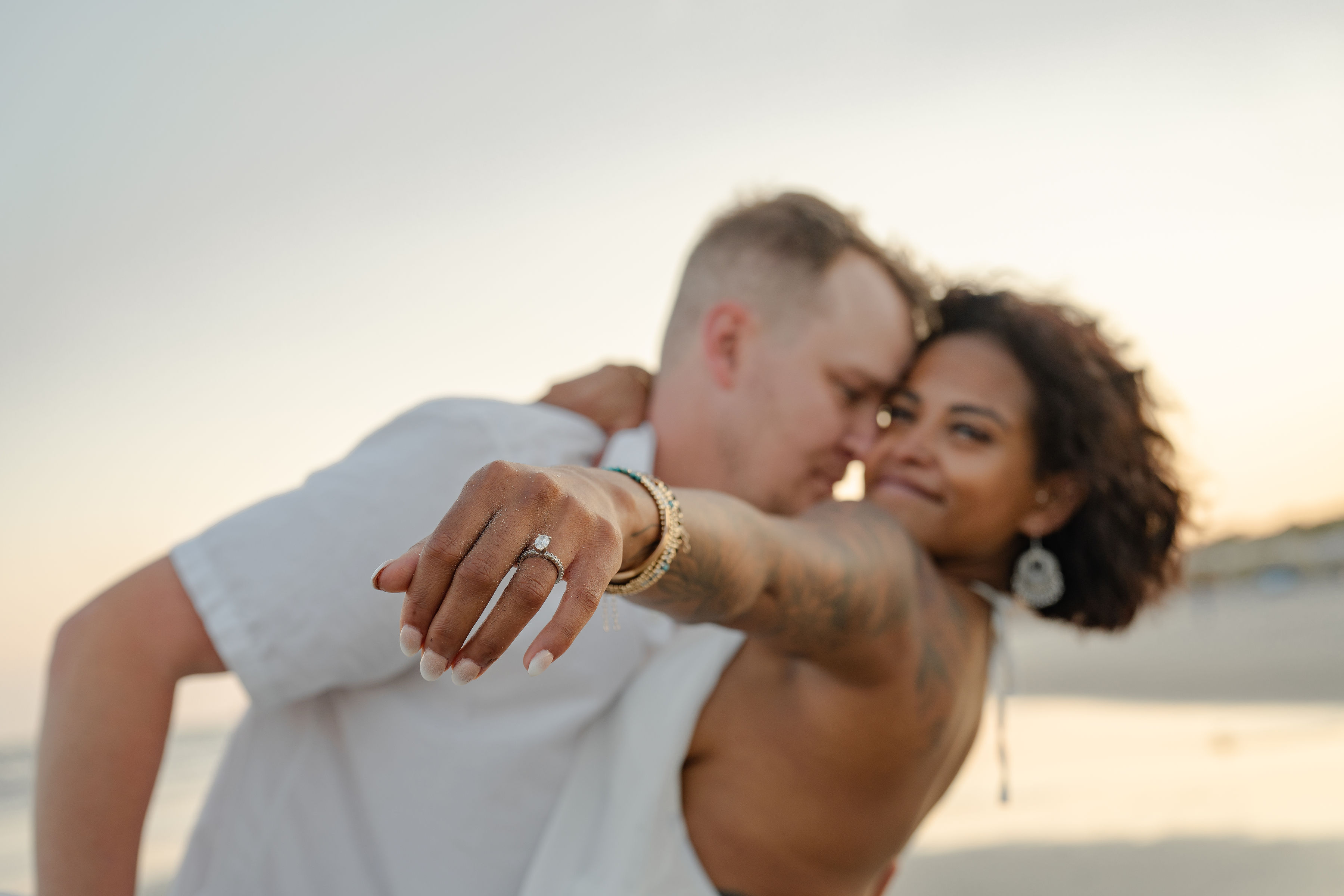 engagement photi of a couple with the women holding her hand in focus with an engagement ring on