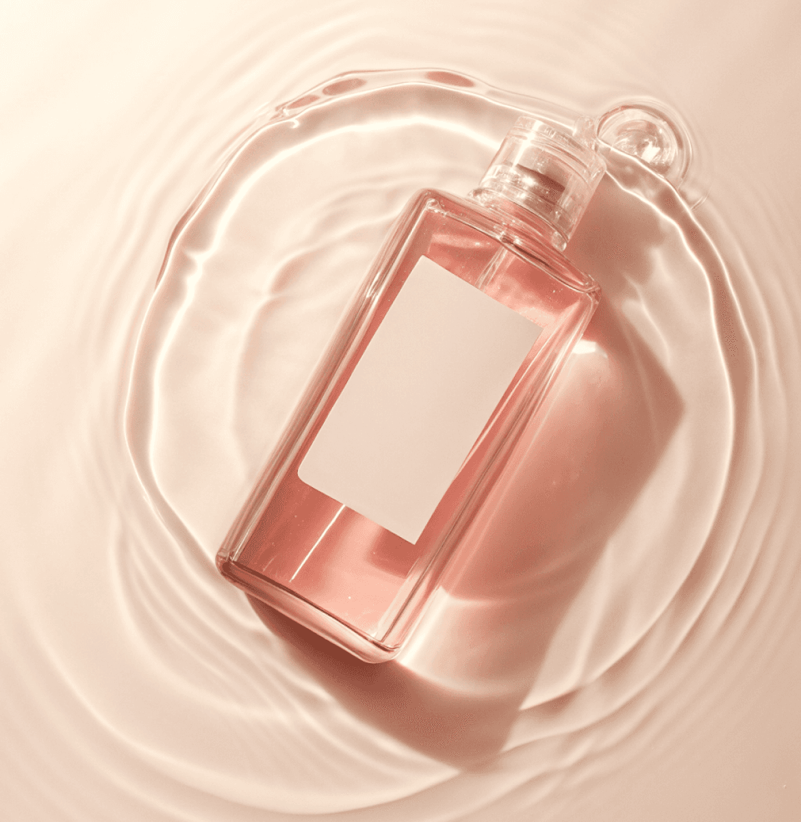 Pink liquid bottle with a blank label floating on rippled water, captured in soft, warm lighting.