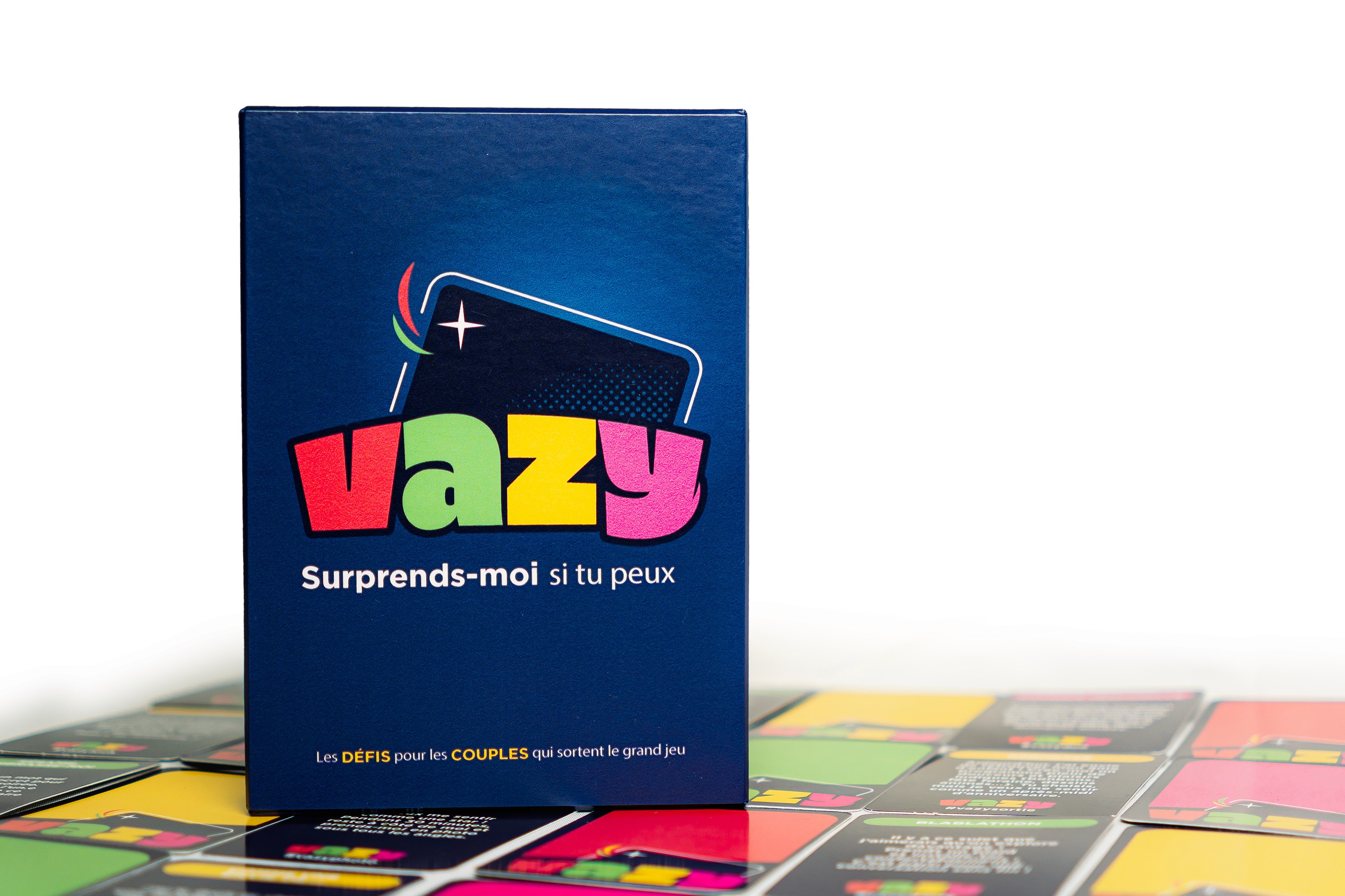 Boîte du jeu “Vazy - Surprends-moi si tu peux” posée sur des cartes colorées étalées.