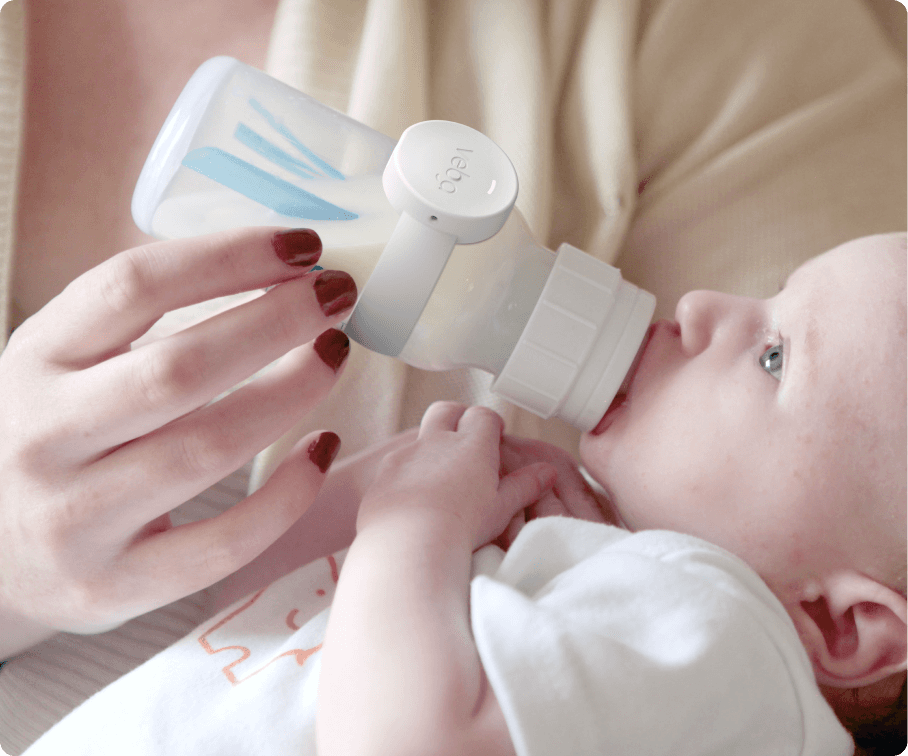 Woman feeding a baby with a smart baby bottle monitor attached to the bottle, tracking feeding data in real-time while ensuring accurate monitoring.