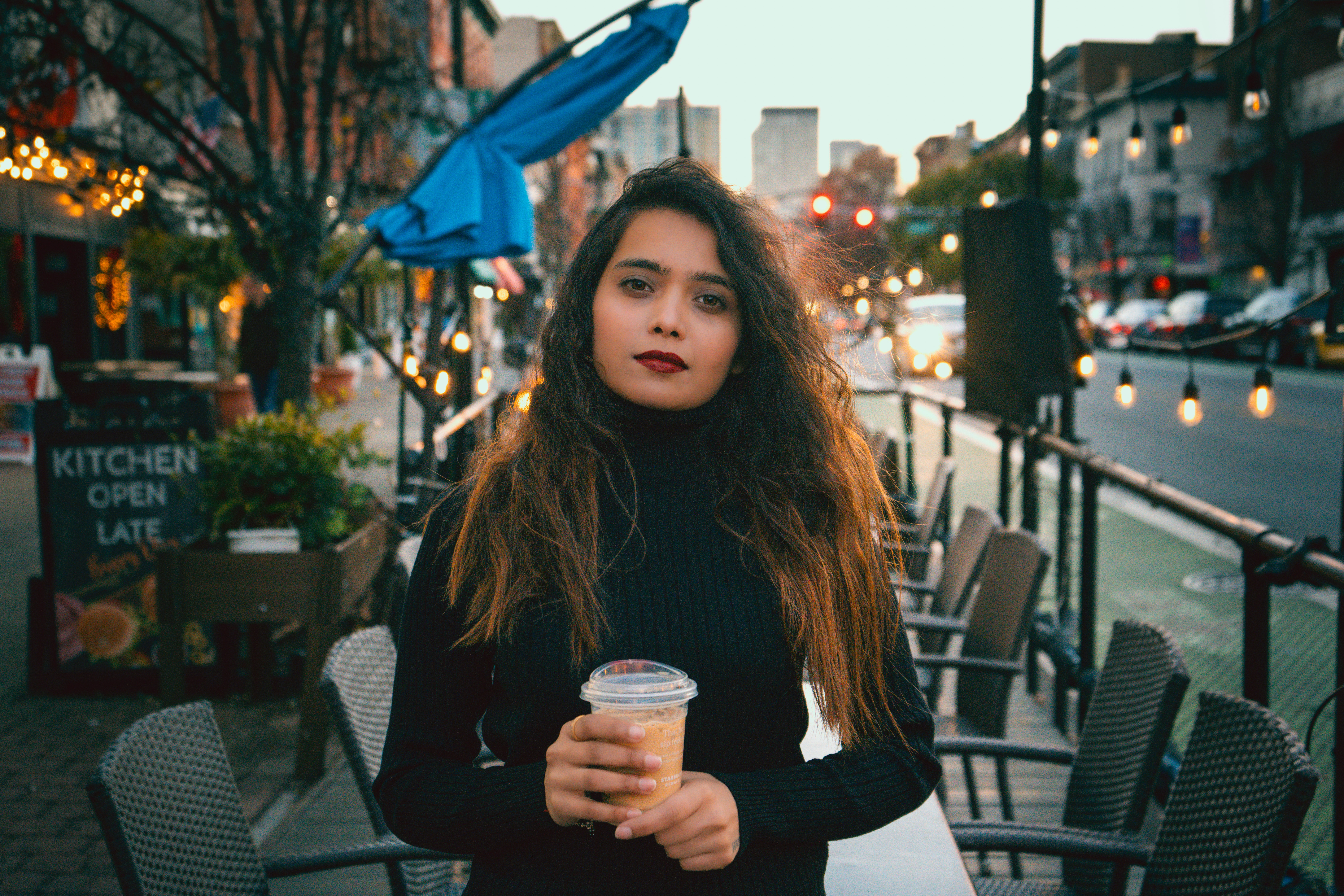a woman holding a cup of coffee on a city street