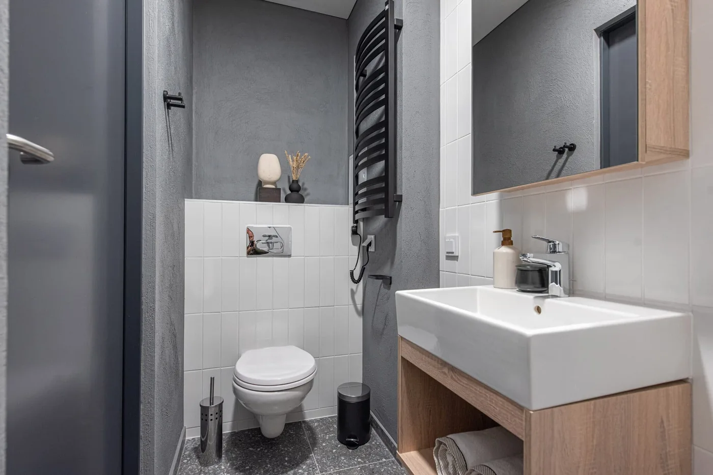 Private bathroom in Vilnius student accommodation with modern sink, toilet, mirror and heated towel rail.